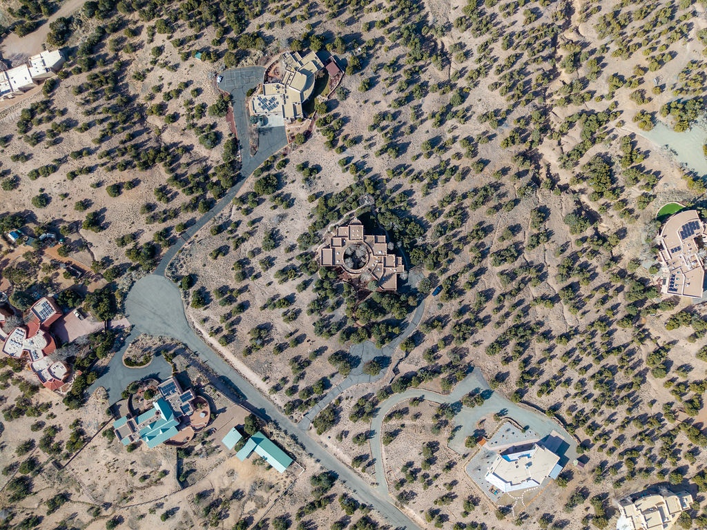 Aerial view of luxury vacation rental properties nestled in a natural desert landscape with scattered vegetation and winding access roads.