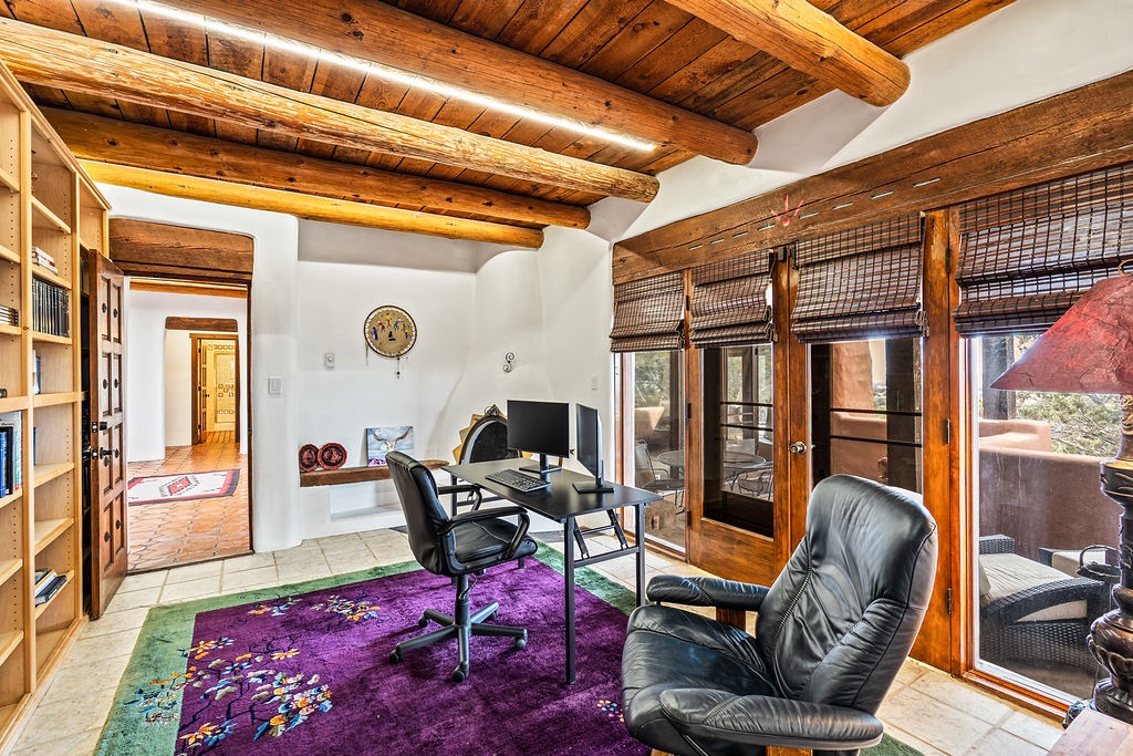 Your private workspace features authentic wooden beams, a comfortable leather chair, and vibrant rugs beneath your feet, with natural light streaming through windows.