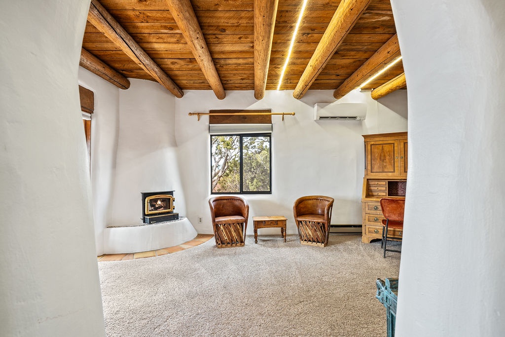 Relax by the cozy fireplace under stunning exposed wood beams in this comfortable living area.