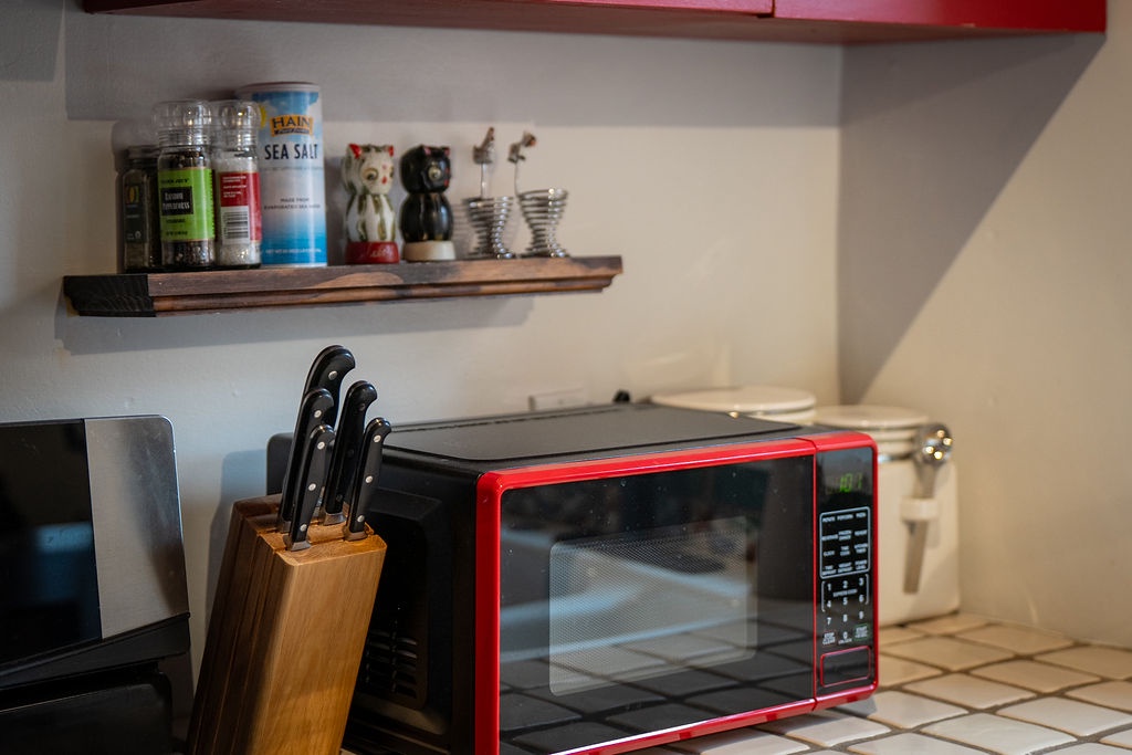 Your well-equipped kitchen features a bright red microwave and thoughtful touches like spices and charming decorative details to make cooking feel like home.