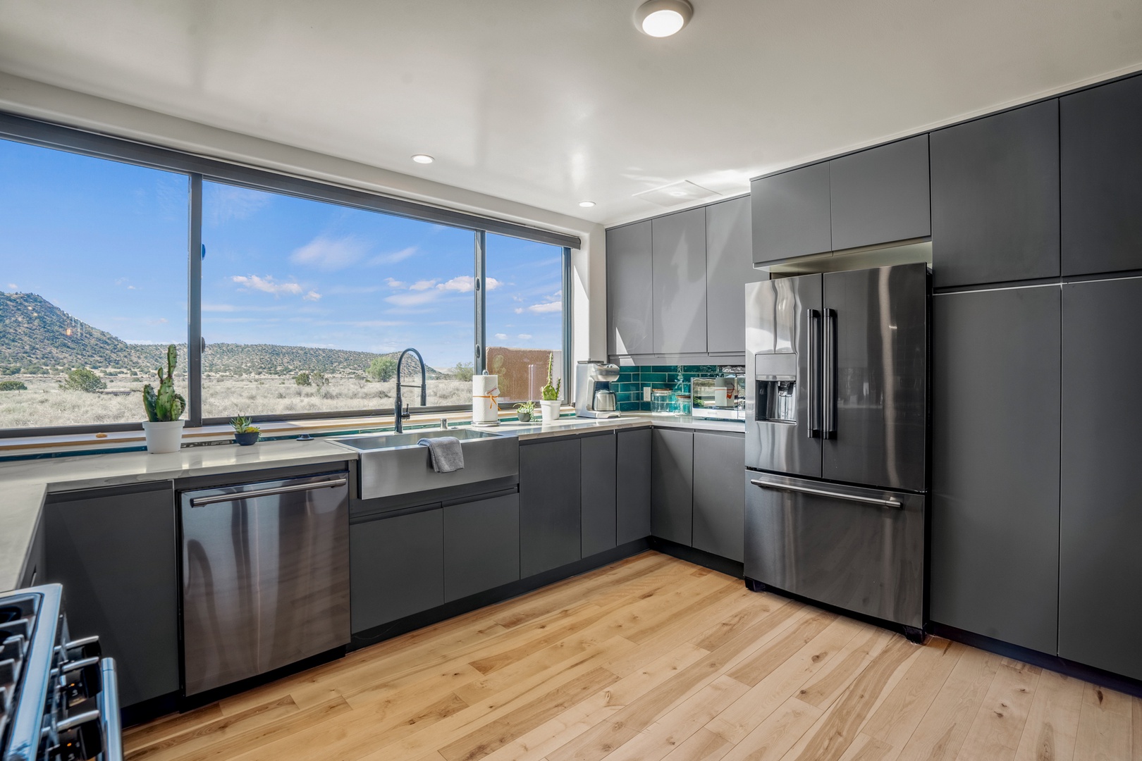 Cook with mountain views through expansive windows in this sleek modern kitchen, featuring stainless steel appliances and rich hardwood floors.
