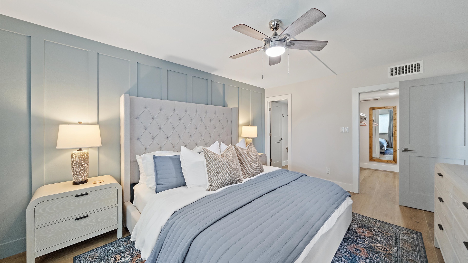 Drift off in your elegant bedroom, with plush bedding, soothing blue accents, and warm lighting creating the perfect retreat.