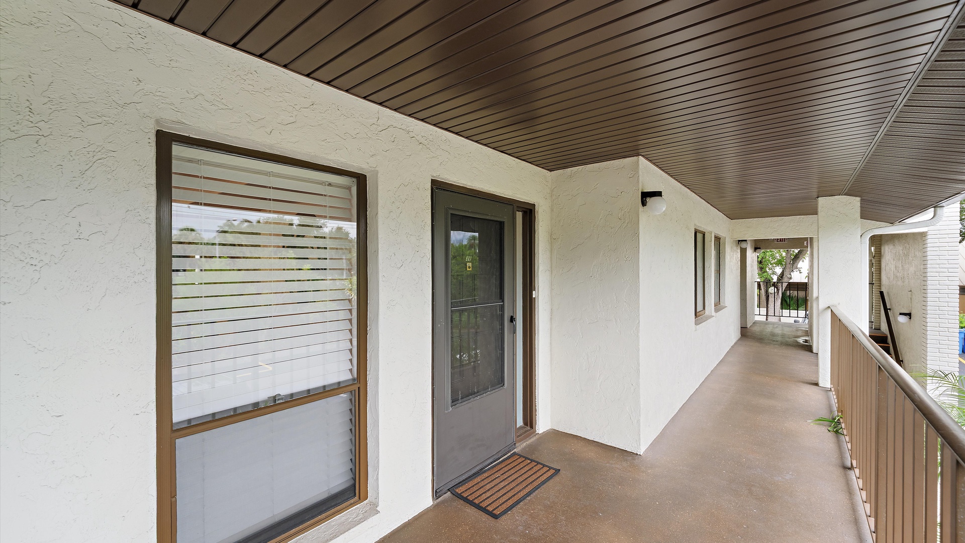 The property features a covered entrance walkway with clean white walls and modern wood-tone accents, providing a welcoming arrival to your retreat.