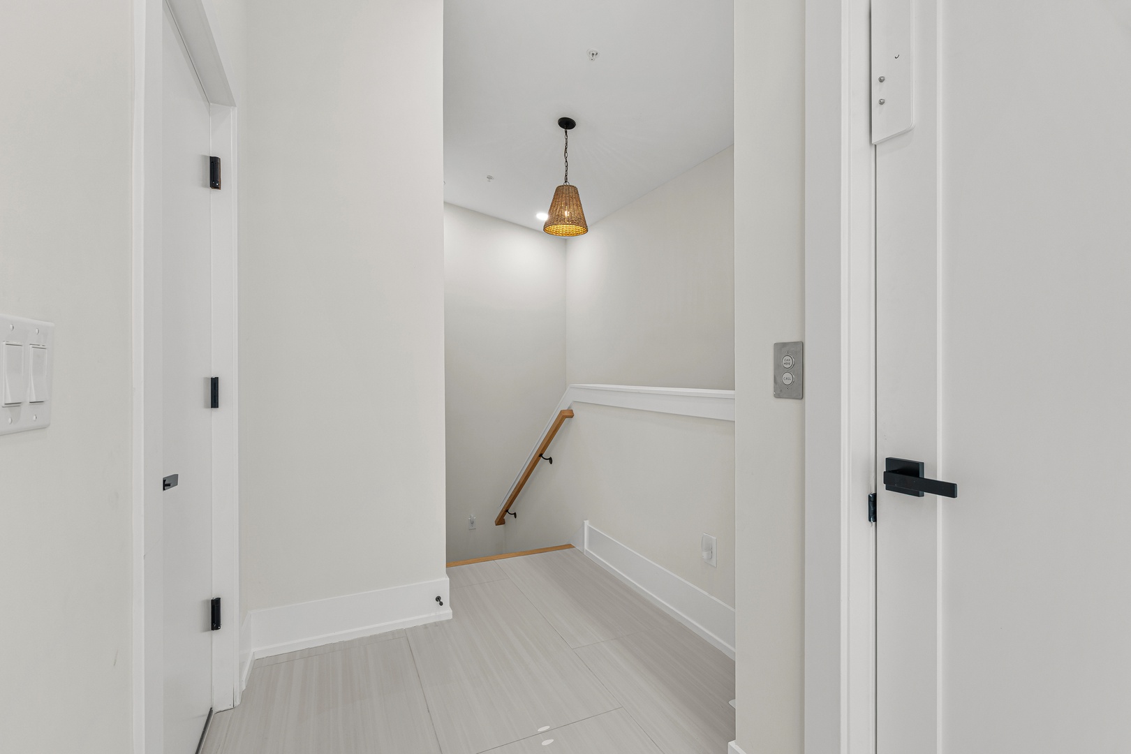 A welcoming hallway with a stylish pendant light and warm wood railing leading you to your upstairs retreat.