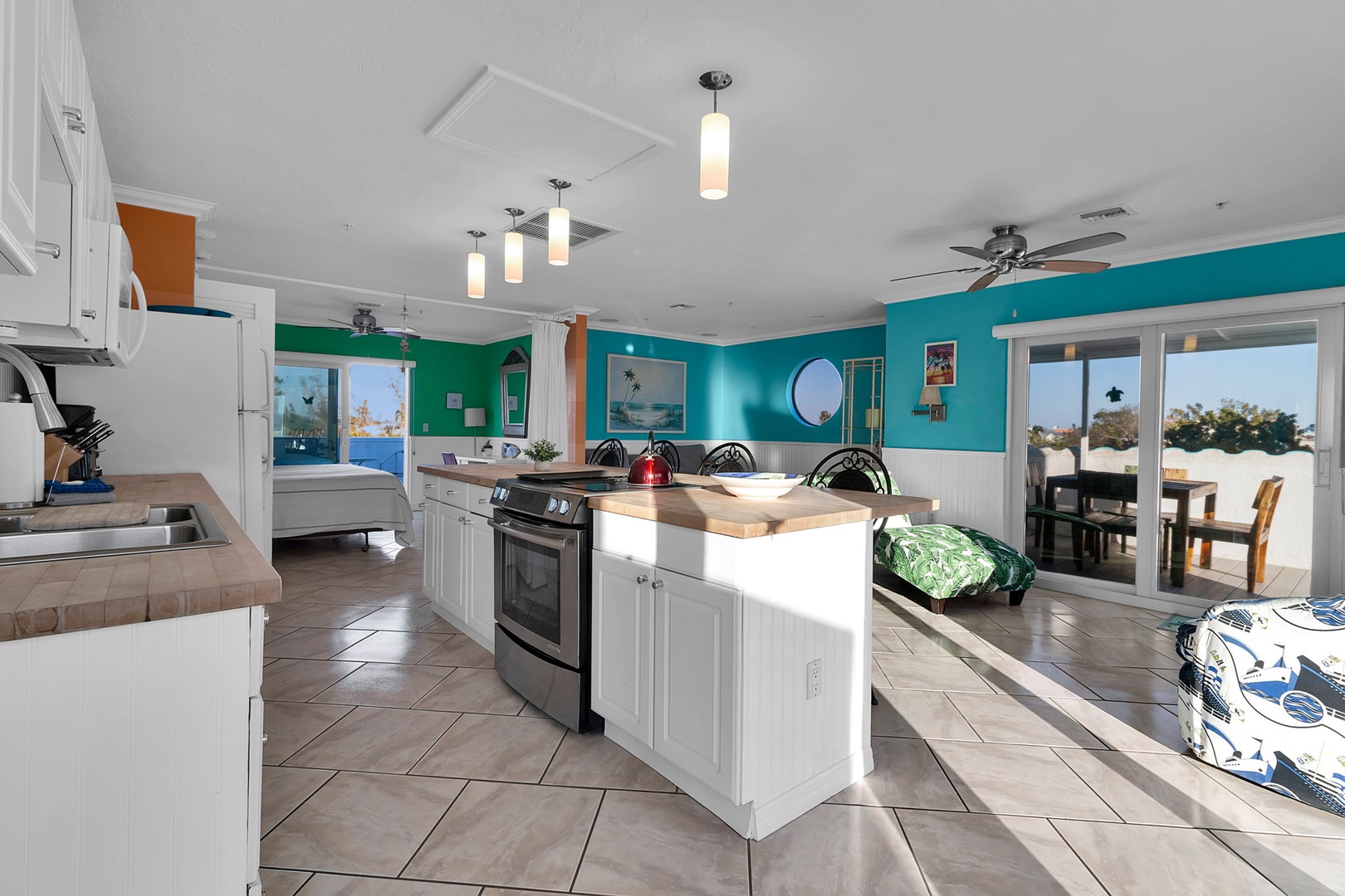 Step into your bright coastal kitchen where sea breezes meet vibrant turquoise walls. Cook, dine, and sip your morning coffee while gazing at ocean views framed by every window.