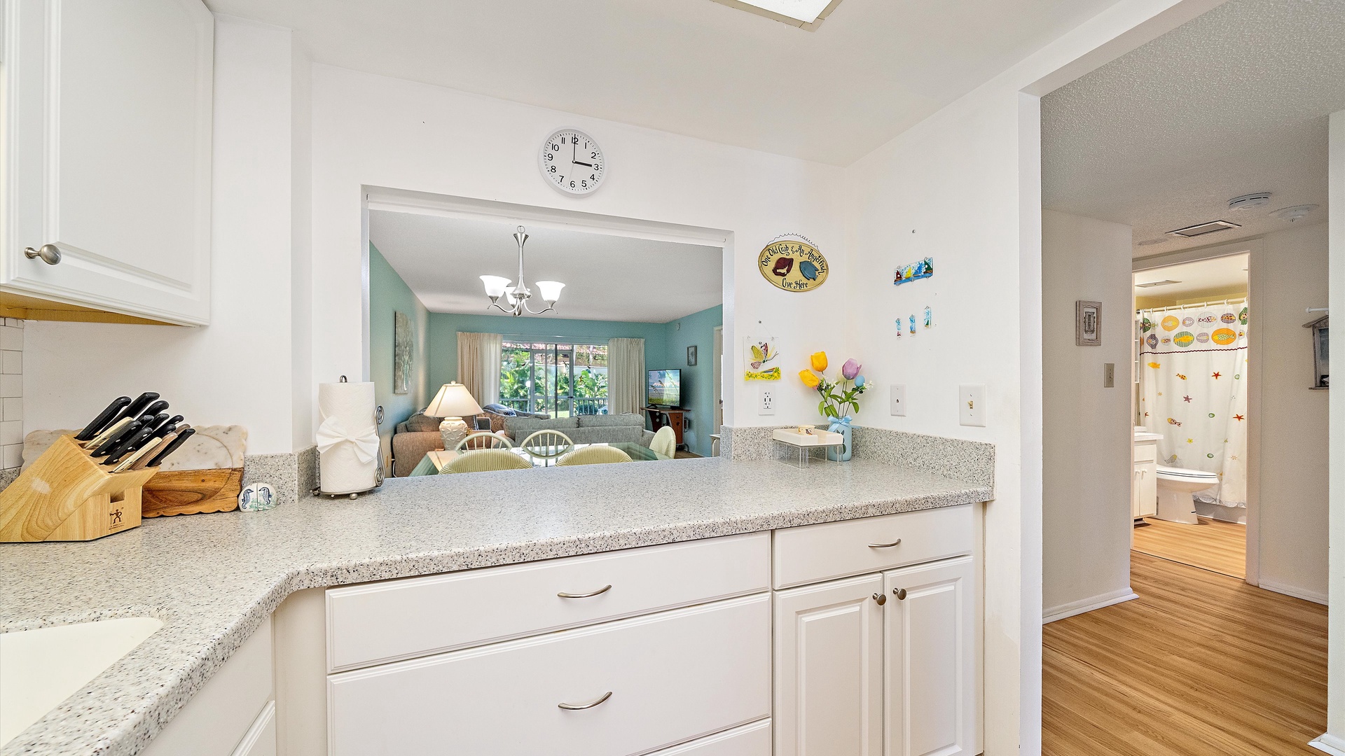 Enjoy your fully equipped kitchen with clean countertops, fresh flowers, and an open layout connecting you to the living room—perfect for cooking and relaxing together.