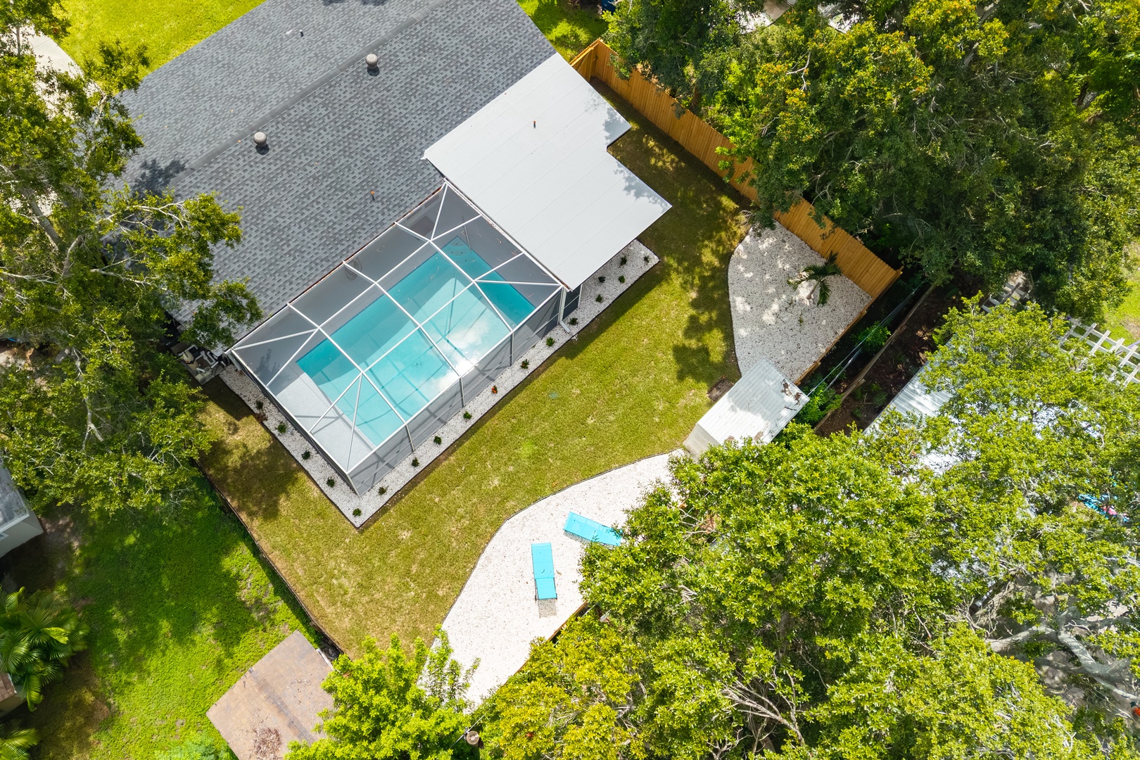 Aerial view of vacation rental featuring enclosed swimming pool area surrounded by lush mature trees and spacious private grounds.