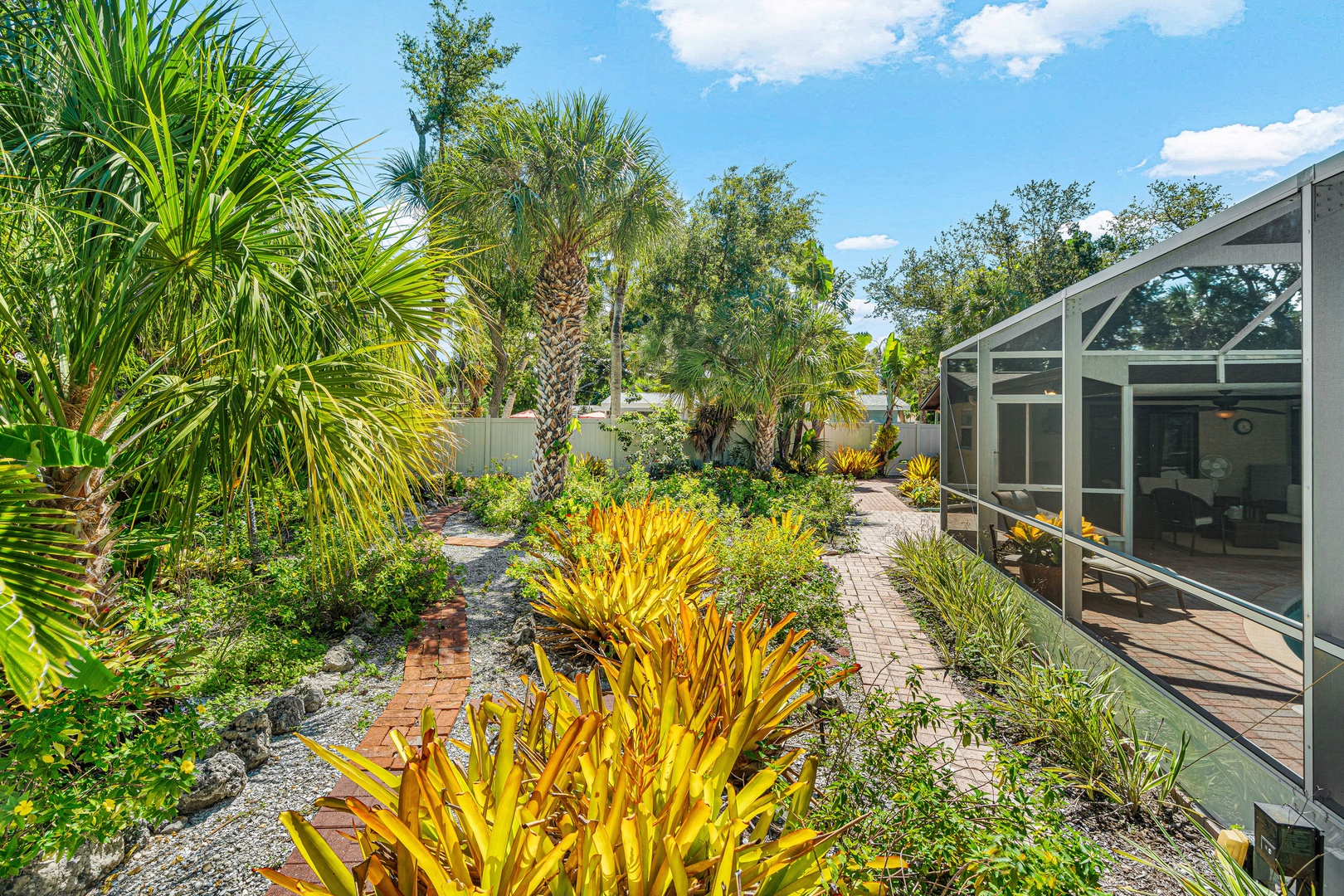 Wander through your private tropical garden, where golden foliage and lush palms frame the pathway to your screened patio—a serene escape under sunny skies.