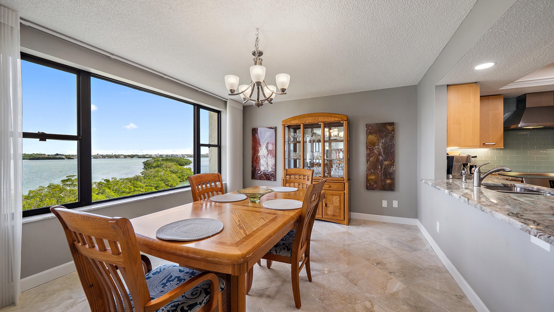 Savor meals with breathtaking water views from your elegant dining space, where warm wood tones and modern comfort create perfect moments.