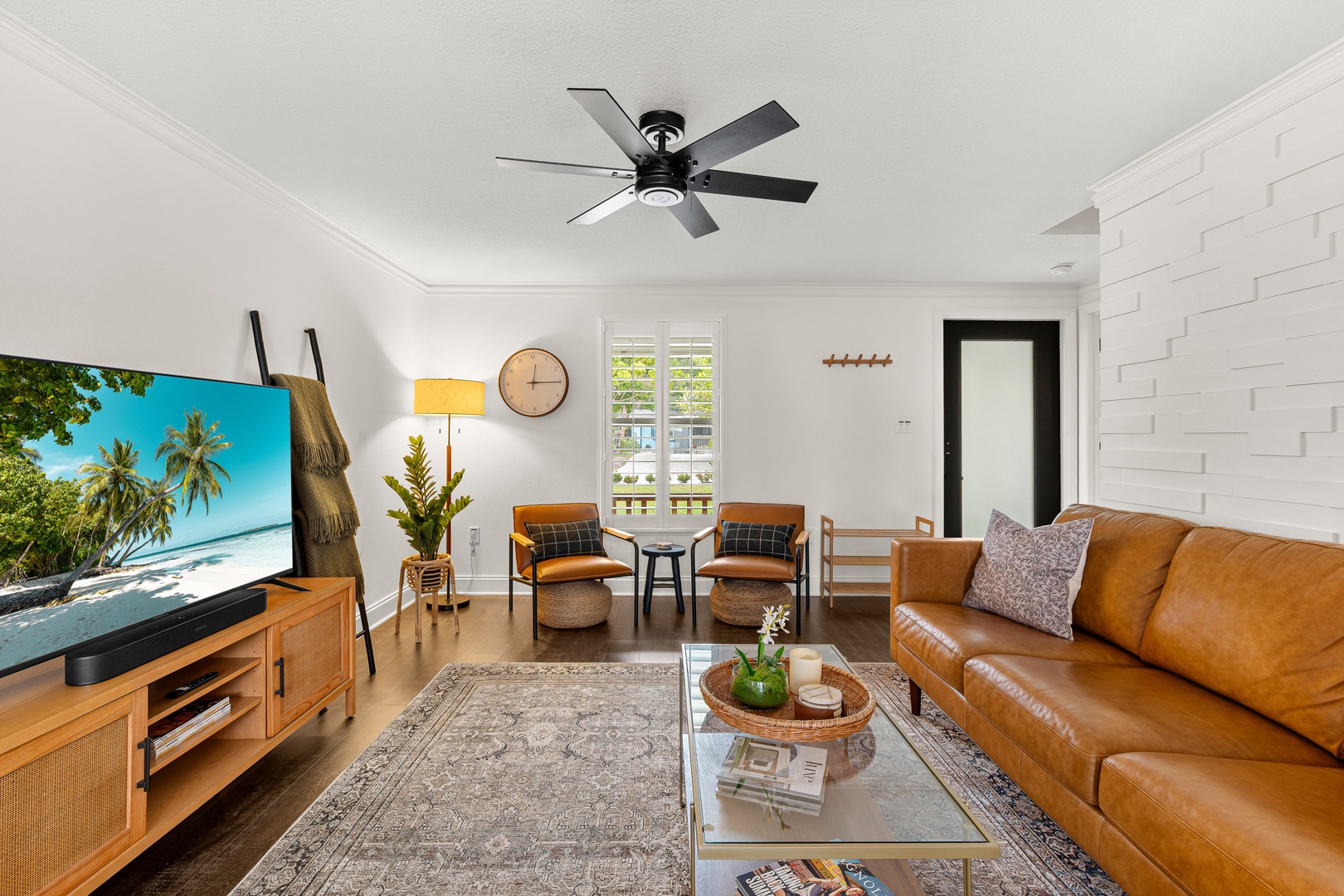 Sink into the leather sofa, feel the ceiling fan's gentle breeze, and let your vacation unfold in this bright, welcoming living space with modern touches and coastal charm.