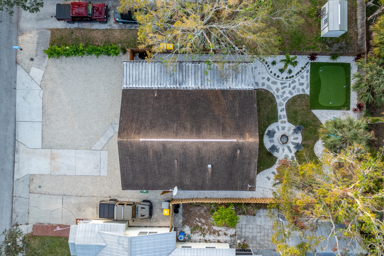 Aerial view of the property showcasing the main building, landscaped grounds with tropical vegetation, and nearby residential street access.