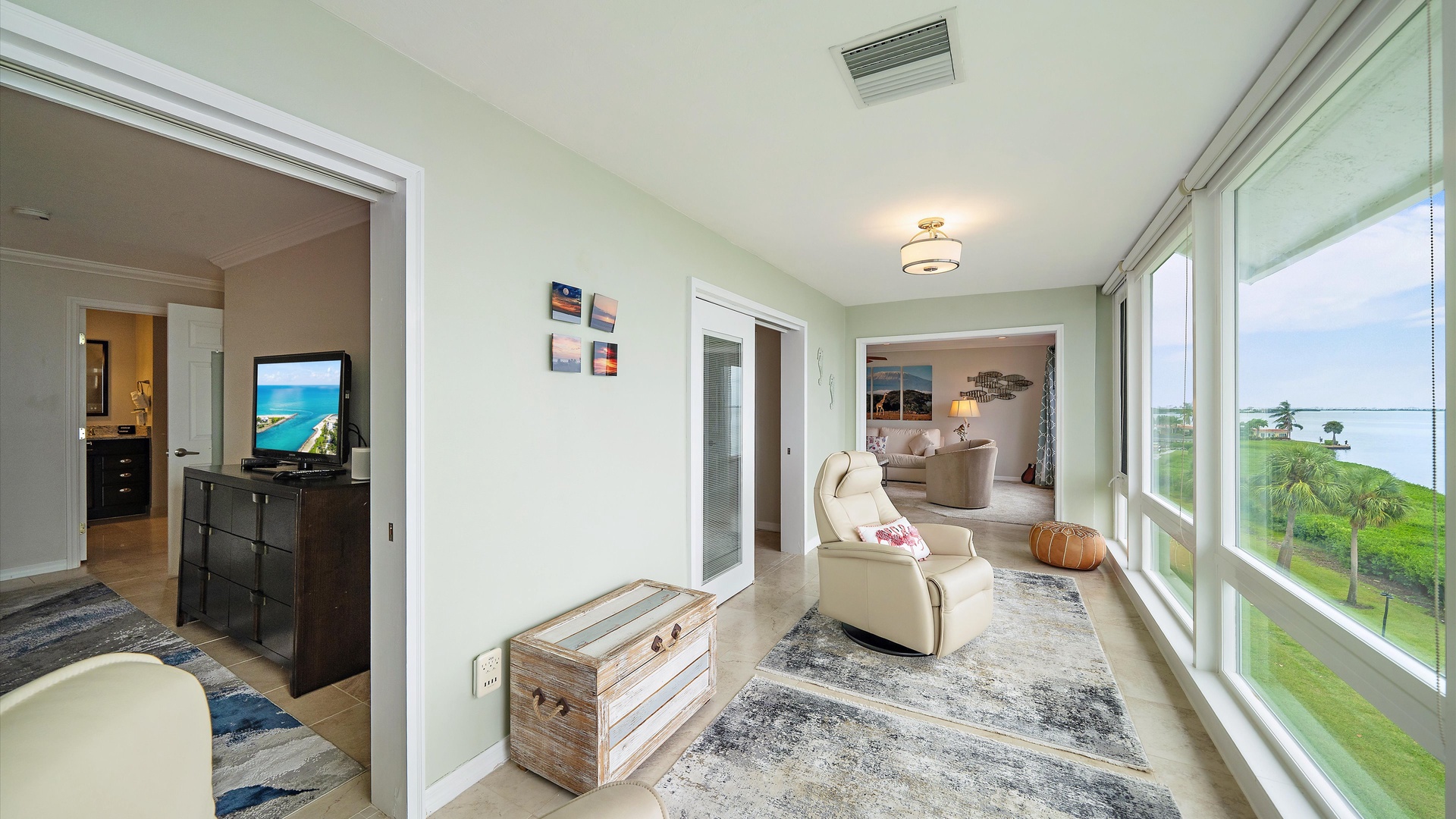 A second place to relax, connected to the main living room and both bedrooms. Comfortable recliners and coastal details make the enclosed sunroom feel like a natural extension of the home.