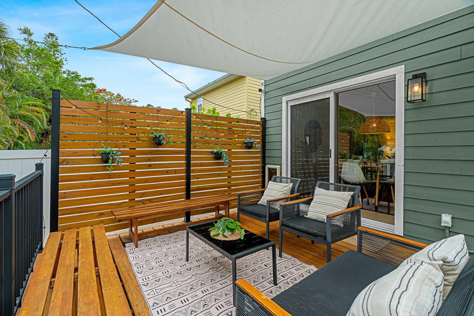 Your private deck invites sunny morning coffees and evening relaxation under a shaded canopy, with stylish lounge seating and lush greenery creating your perfect outdoor retreat.