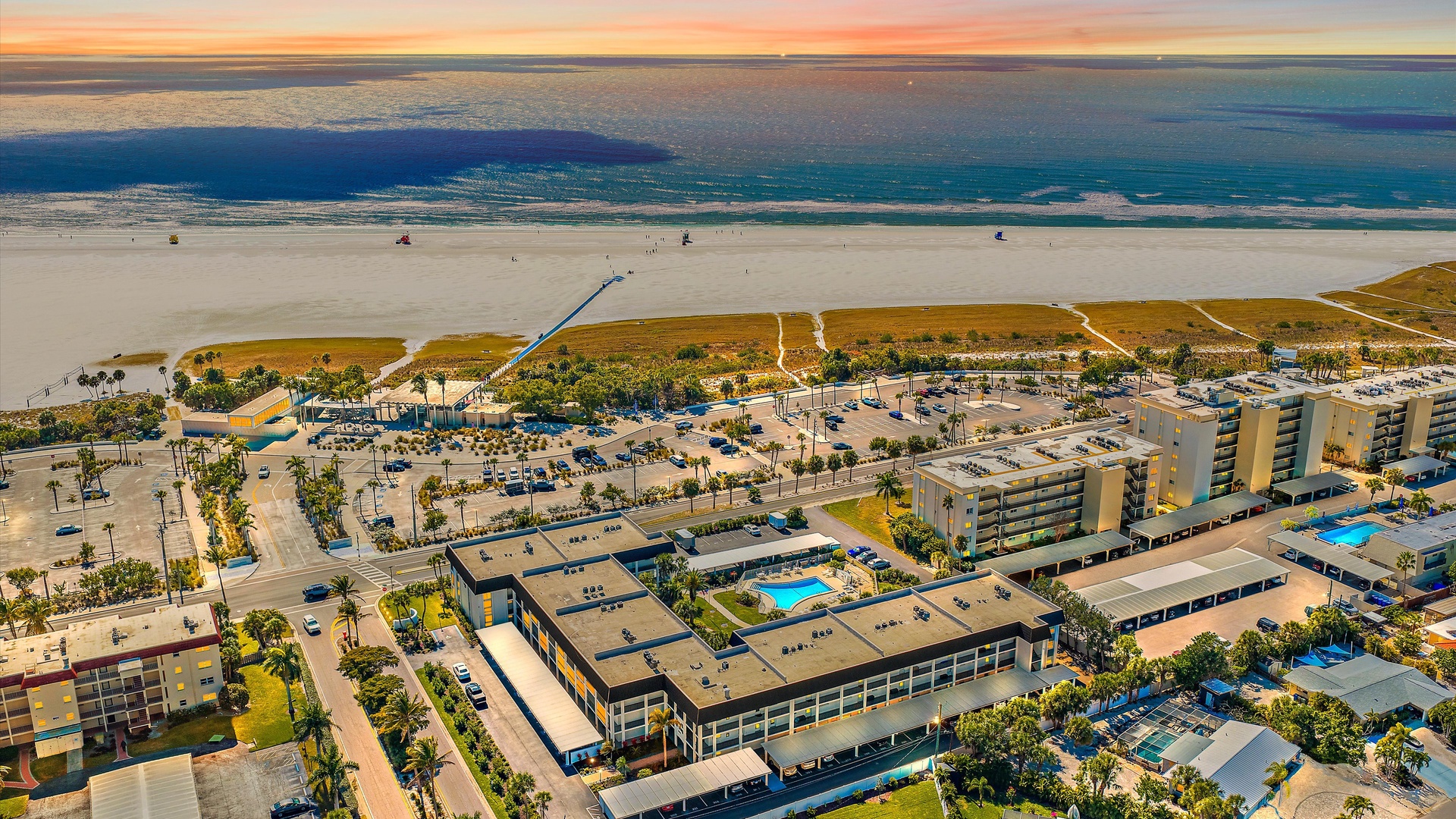 Beachfront property complex showcasing stunning coastal architecture with direct beach access and golden hour lighting over the ocean waves.