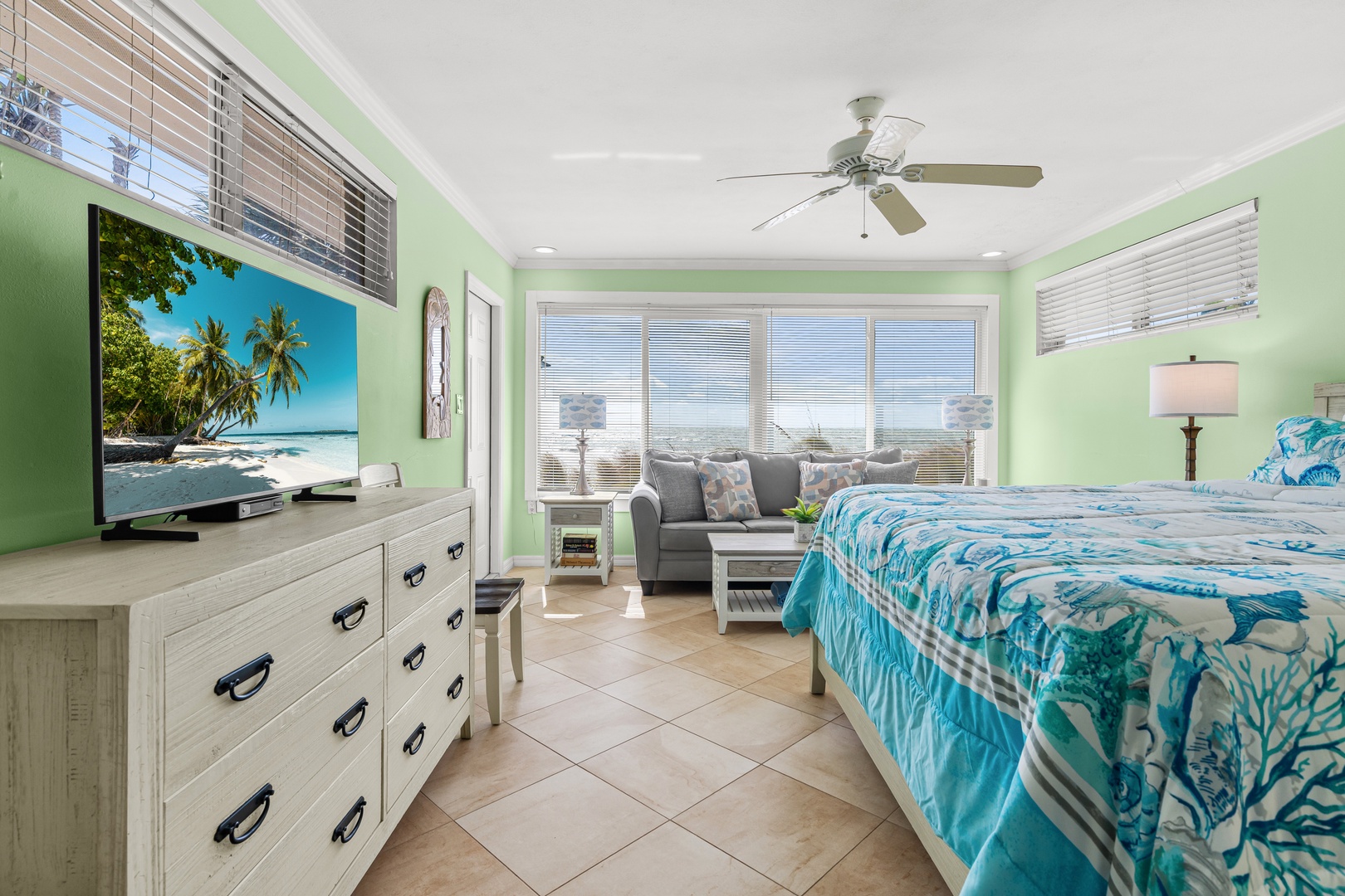 Your coastal bedroom awaits with ocean-inspired decor, comfortable seating, and a ceiling fan for tropical comfort.