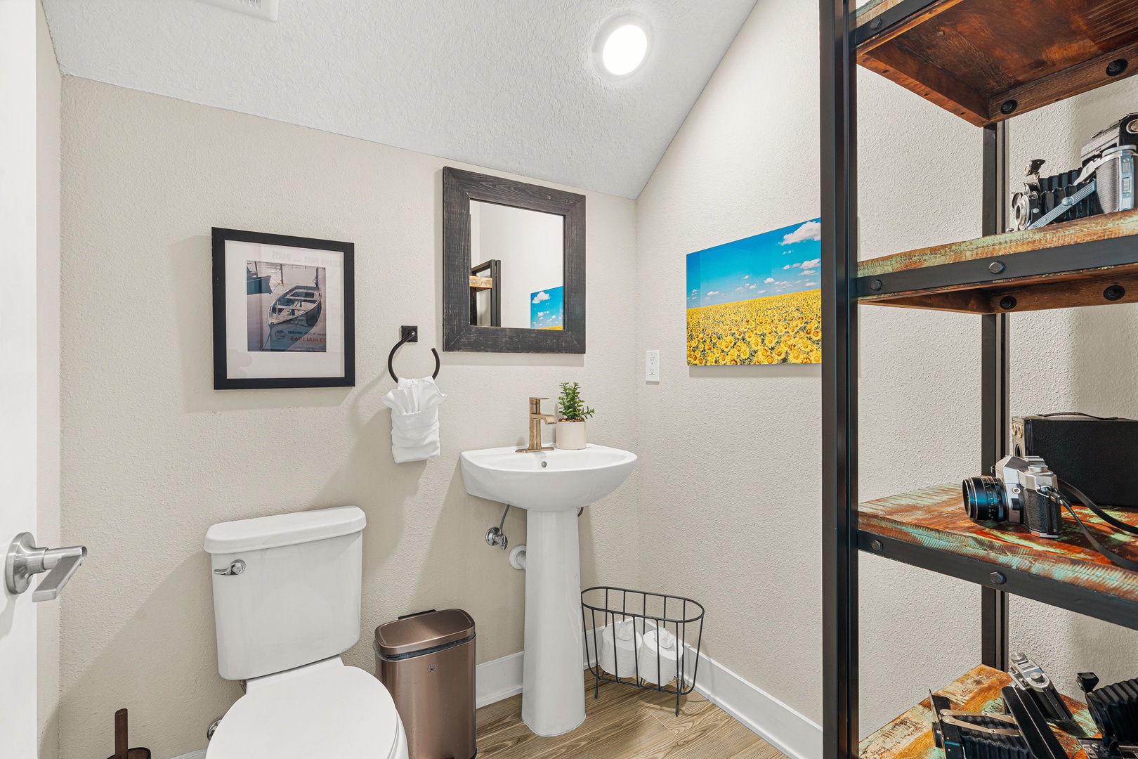 Step into a bright, inviting bathroom where rustic industrial shelving meets modern comfort. The pedestal sink and vaulted ceiling create an airy feel you'll love.