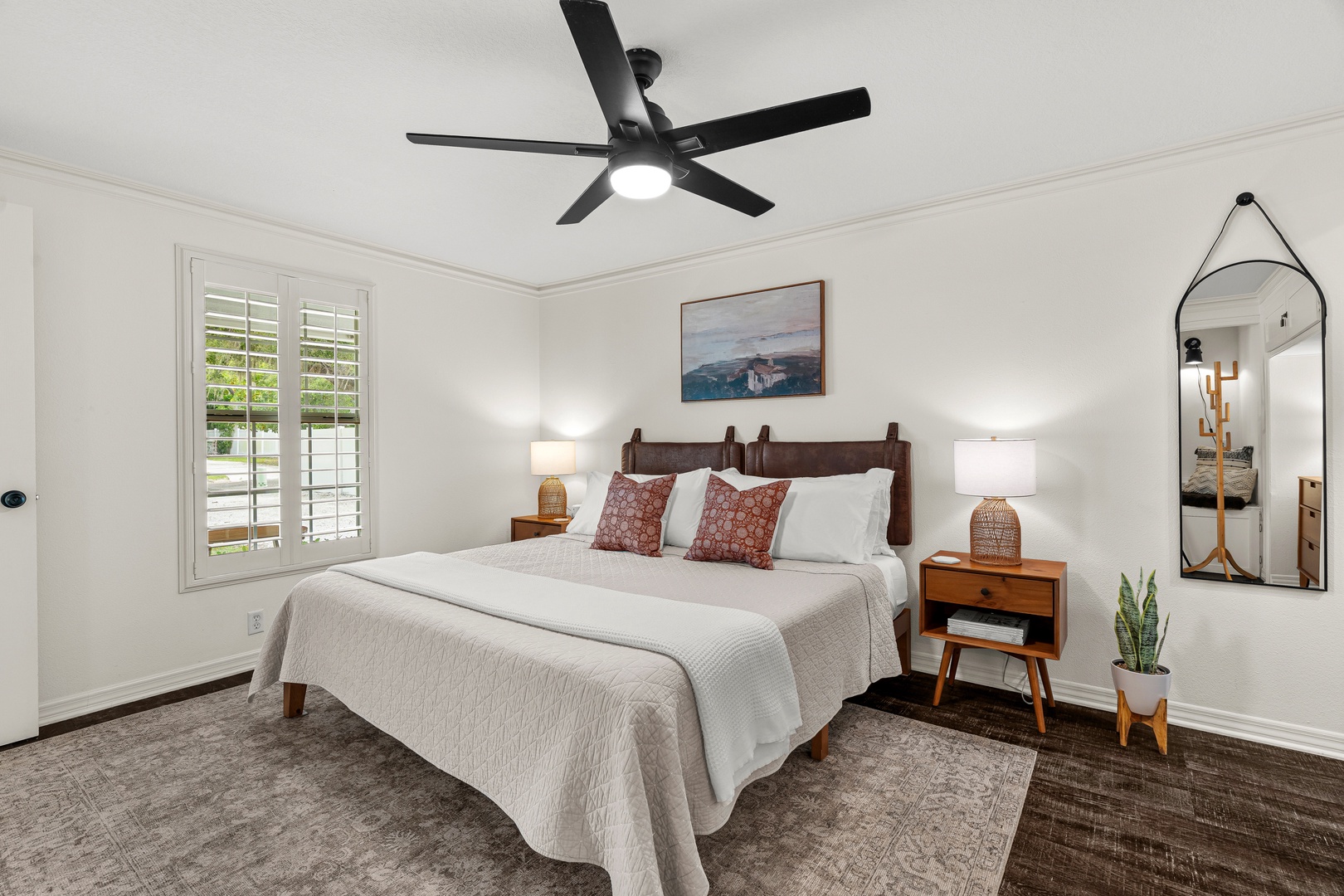 Step into your serene retreat with a plush bed dressed in crisp linens, warm lighting, and thoughtful touches. Plantation shutters invite gentle light while a ceiling fan keeps you comfortable year-round.