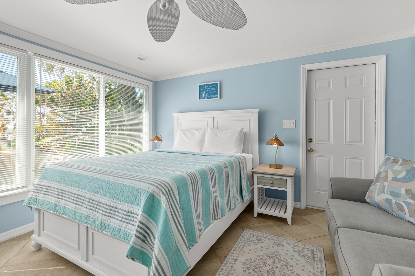 Drift off in your bright, airy bedroom with coastal blue walls and crisp white linens, where morning light streams through large windows.