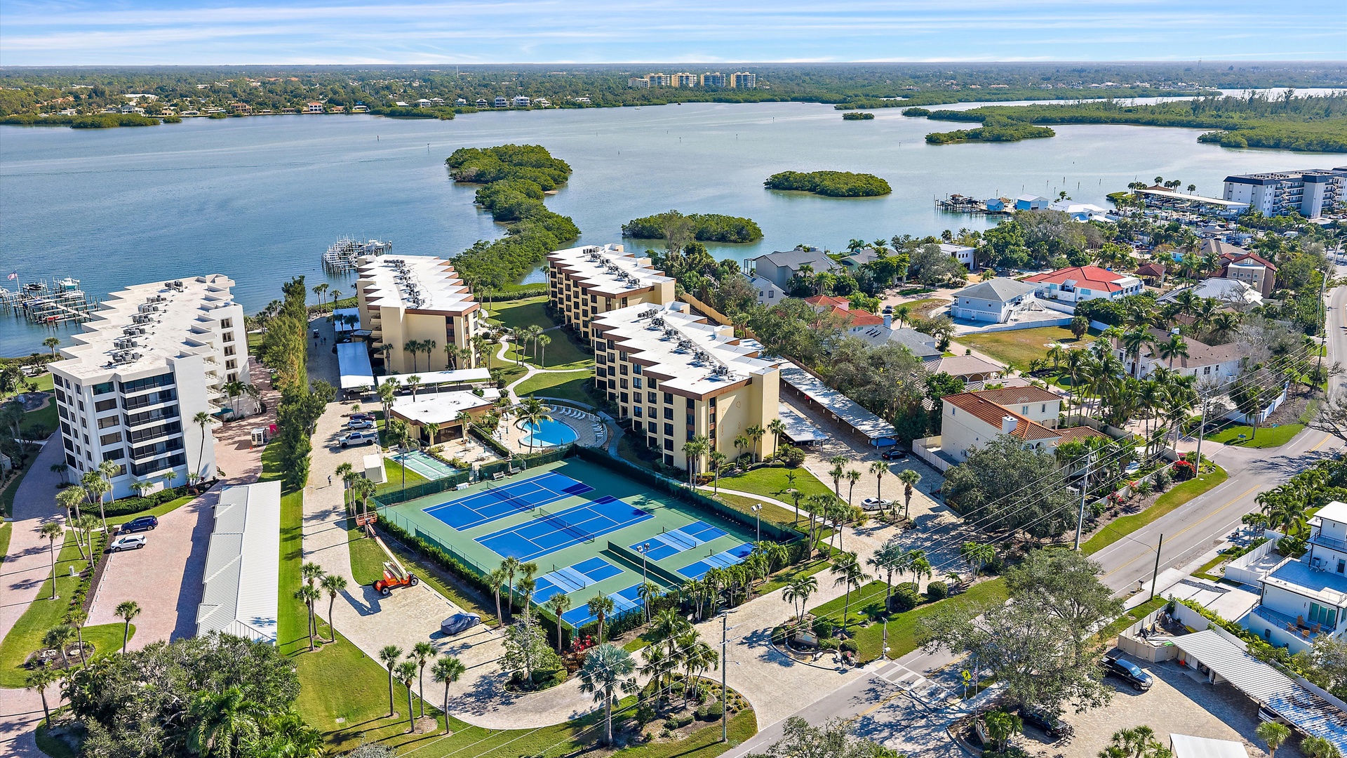 Waterfront resort community featuring tennis courts, pools, and marina access on scenic bay waters with tropical landscaping.