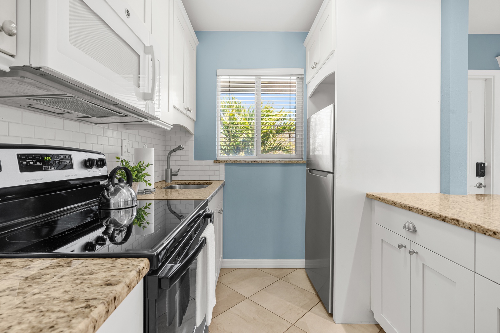 Your bright galley kitchen features granite counters, white cabinets, and stainless appliances with a cheerful view.