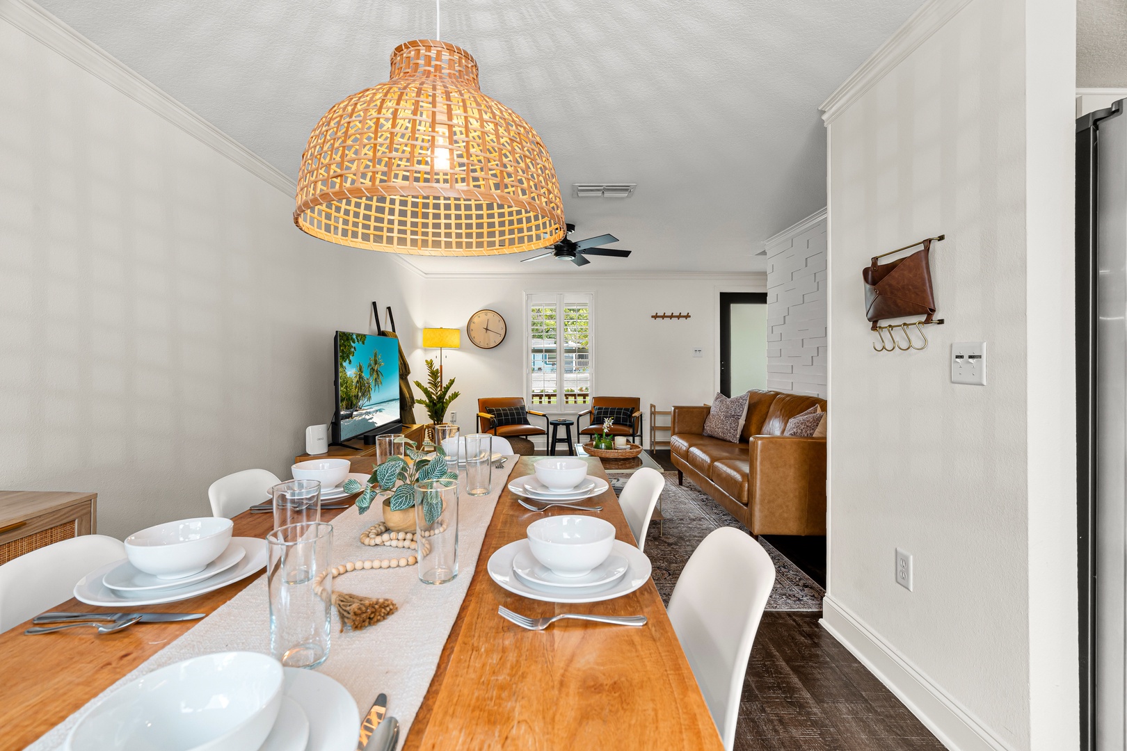 Picture yourself gathering around this welcoming dining table, where shared meals and laughter flow beneath the warm glow of woven lighting. The open layout invites easy conversation with loved ones relaxing nearby.
