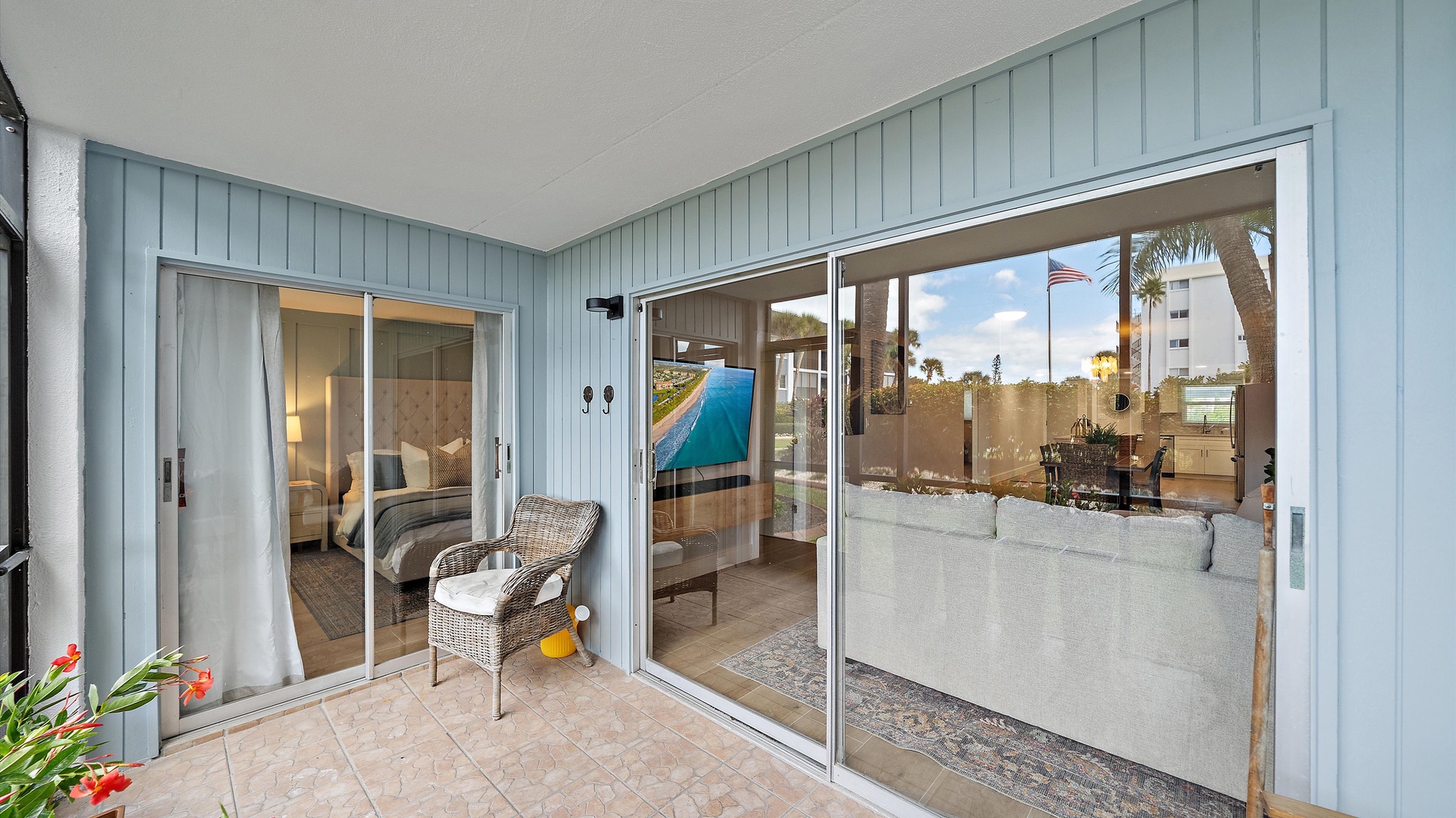Step onto your private balcony where wicker chairs invite morning coffee moments, while floor-to-ceiling glass doors frame views of the sparkling pool below.