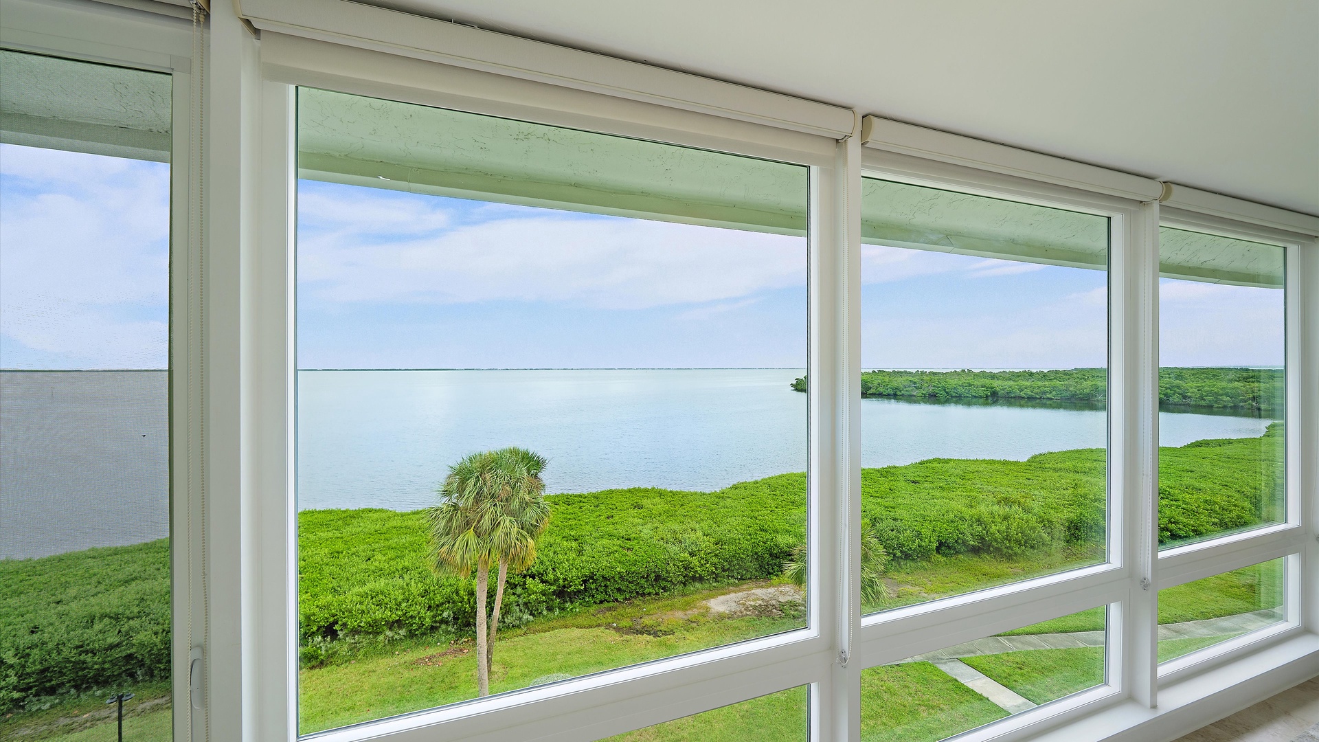 Open bay water and a green mangrove shoreline, framed by the penthouse windows. This is the quiet, distinctly Longboat Key setting that makes an extended waterfront stay so appealing.