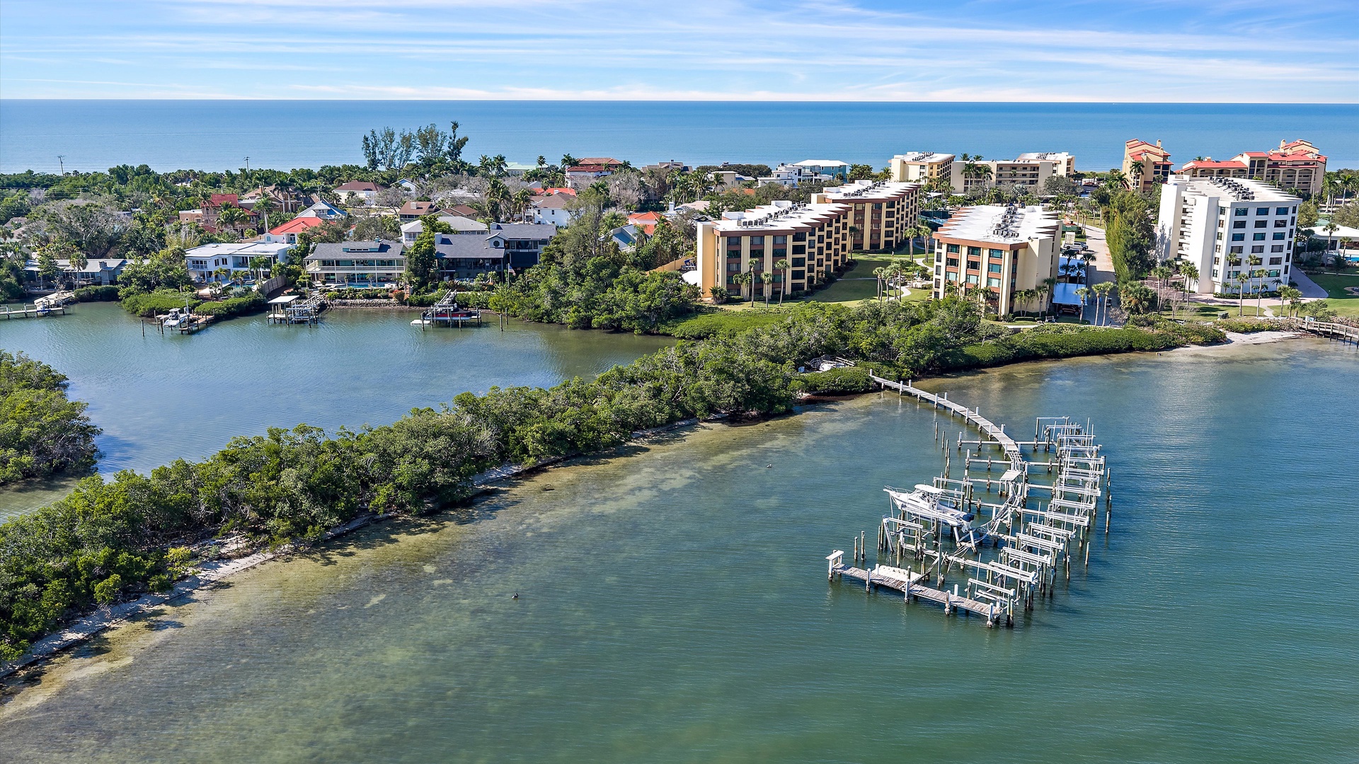 Aerial view of the coastal resort area featuring waterfront buildings and marina facilities near pristine tropical waters.