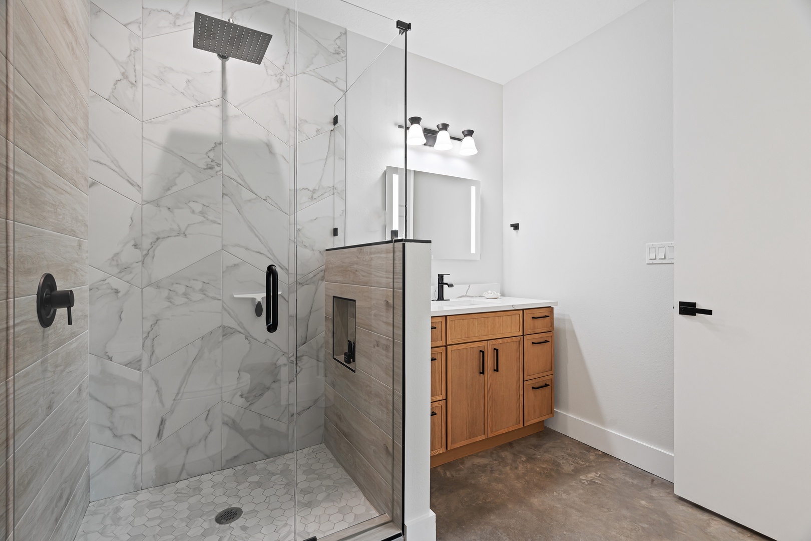 Step into your private spa-like retreat with a stunning marble-tiled walk-in shower and warm wood vanity, where modern luxury meets serene comfort.