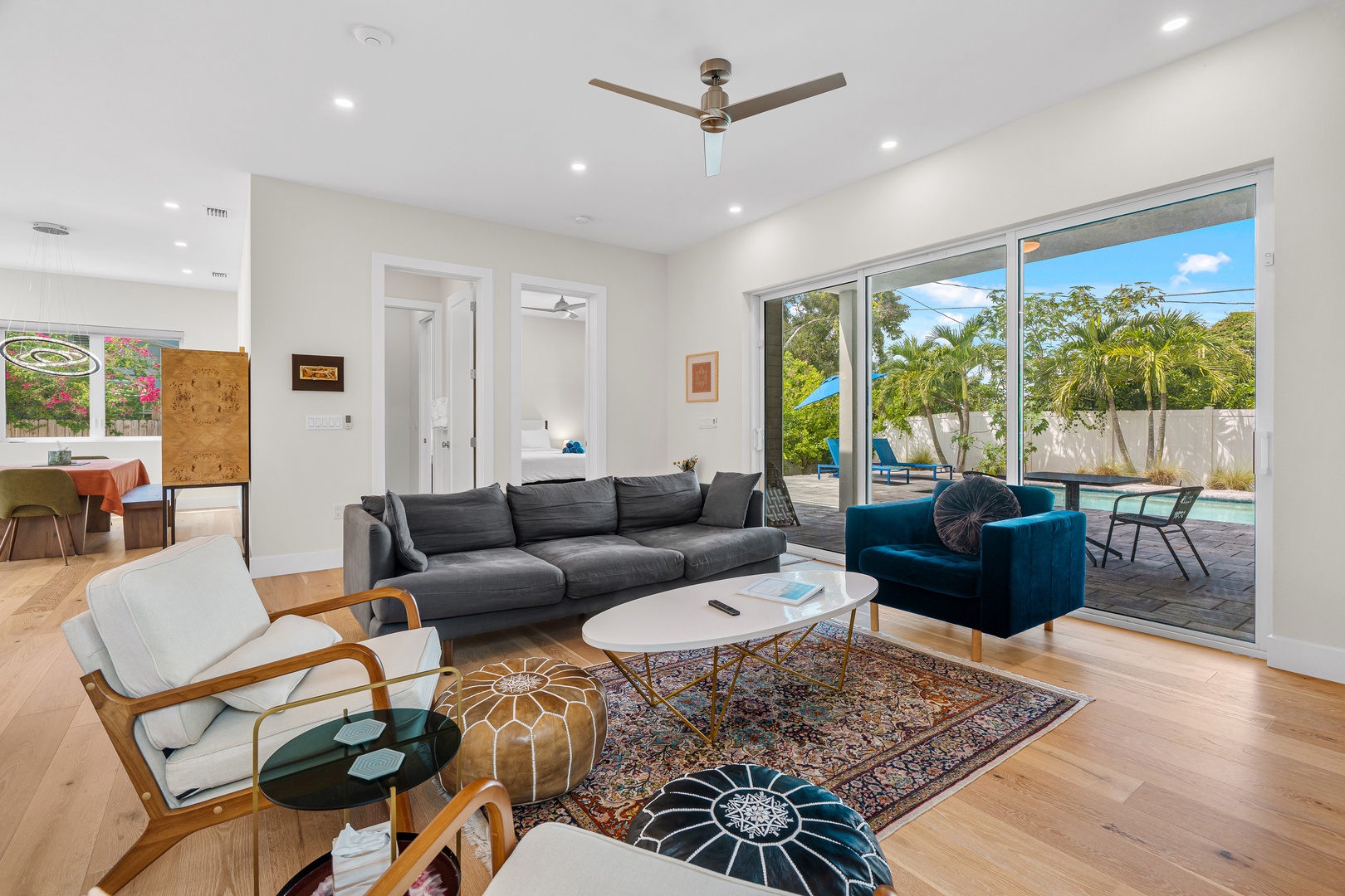 Sink into the plush sofa and let the natural light energize your day. Through the sliding glass doors, your private pool awaits, framed by swaying palms and sunny skies.
