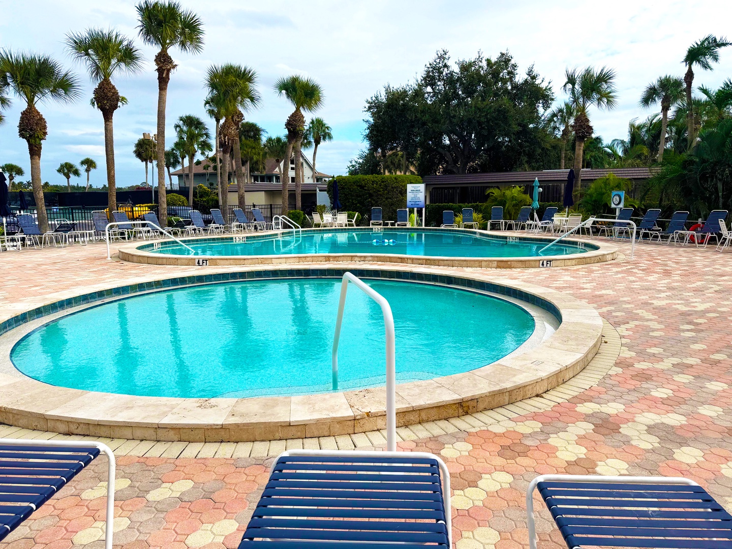Two pristine swimming pools surrounded by tropical palms and comfortable loungers create the perfect outdoor retreat for relaxation.