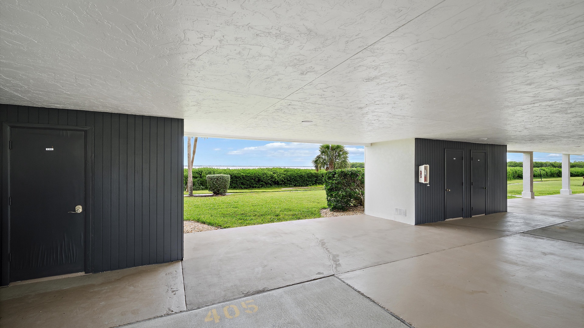 Covered parking beneath the building adds convenience to everyday arrivals and departures. Green lawns and landscaped grounds lie just beyond the carport.