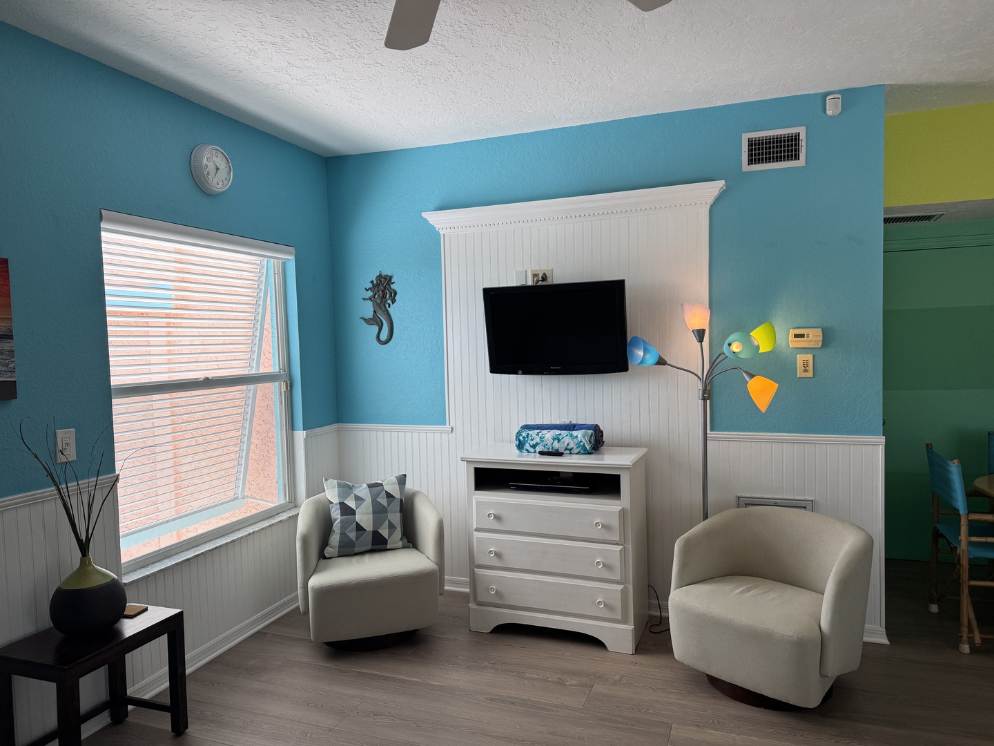 Unwind in your cheerful beach-themed retreat with vibrant turquoise walls and coastal accents. Two comfy chairs invite you to relax while catching up on your favorite shows.