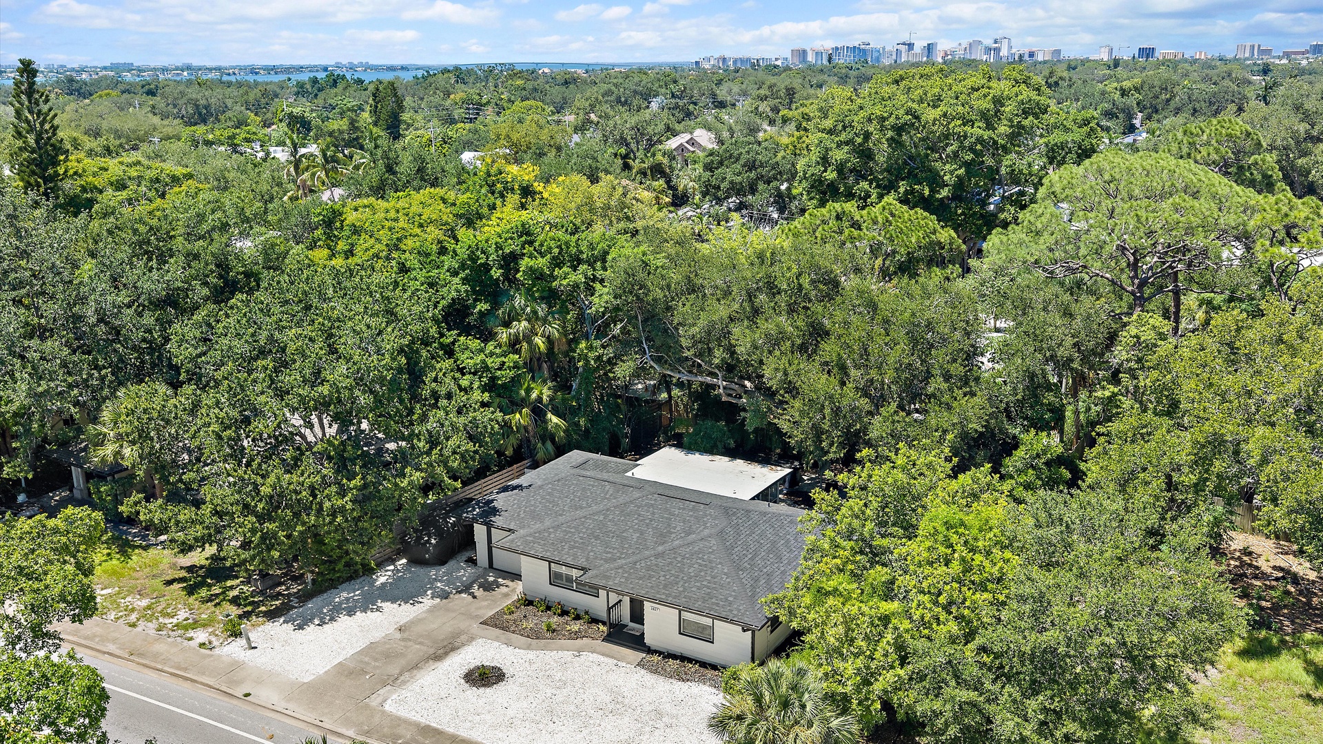 Nestled in a lush, tree-filled neighborhood with a city skyline in the distance, the property offers a peaceful retreat surrounded by natural beauty.