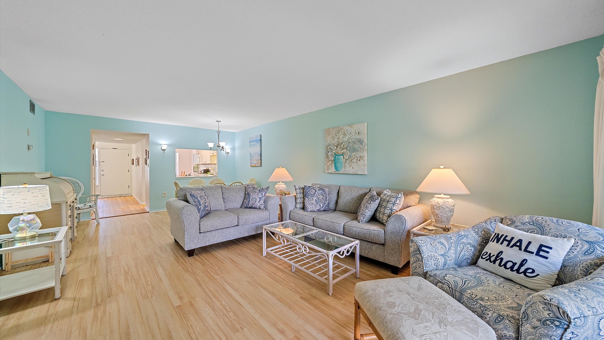 Unwind in your spacious living room with coastal charm—soft blues, comfortable seating, and serene artwork create the perfect retreat after beach adventures.