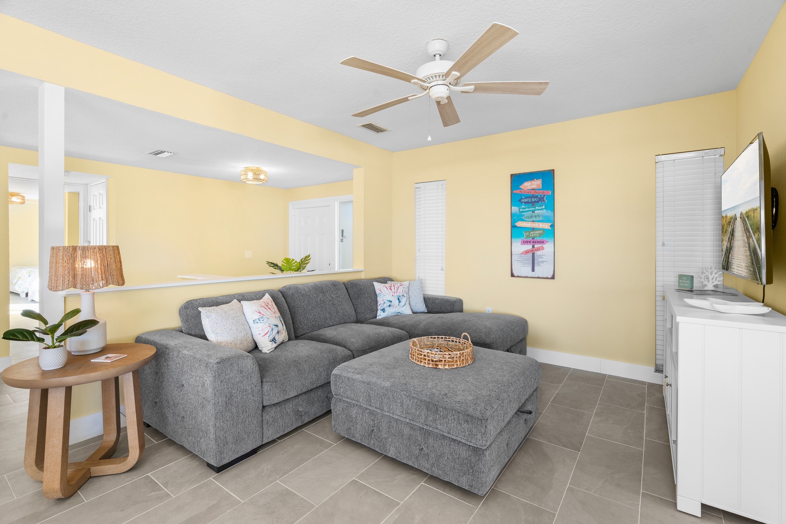 Relax in your bright living room with comfortable sectional sofa, ceiling fan, and entertainment center for cozy evenings.