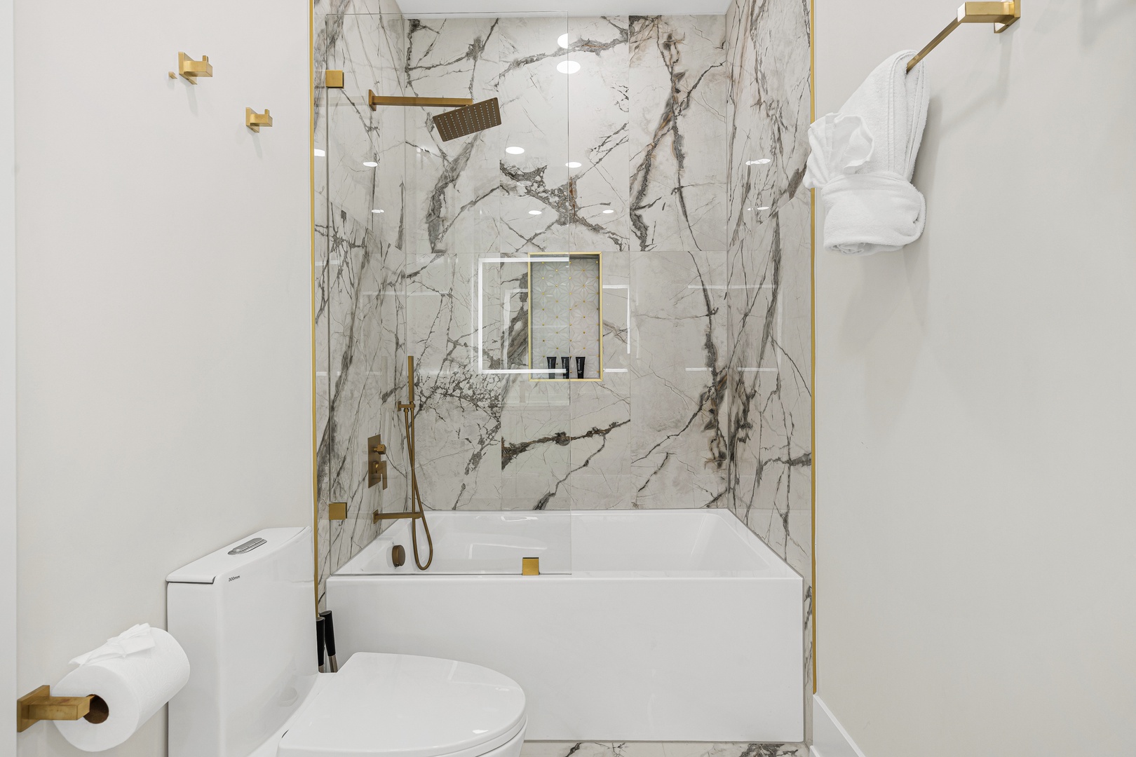 Slip into your private sanctuary with a soaking tub framed by stunning marble-veined walls and luxe gold fixtures that catch the light just right.