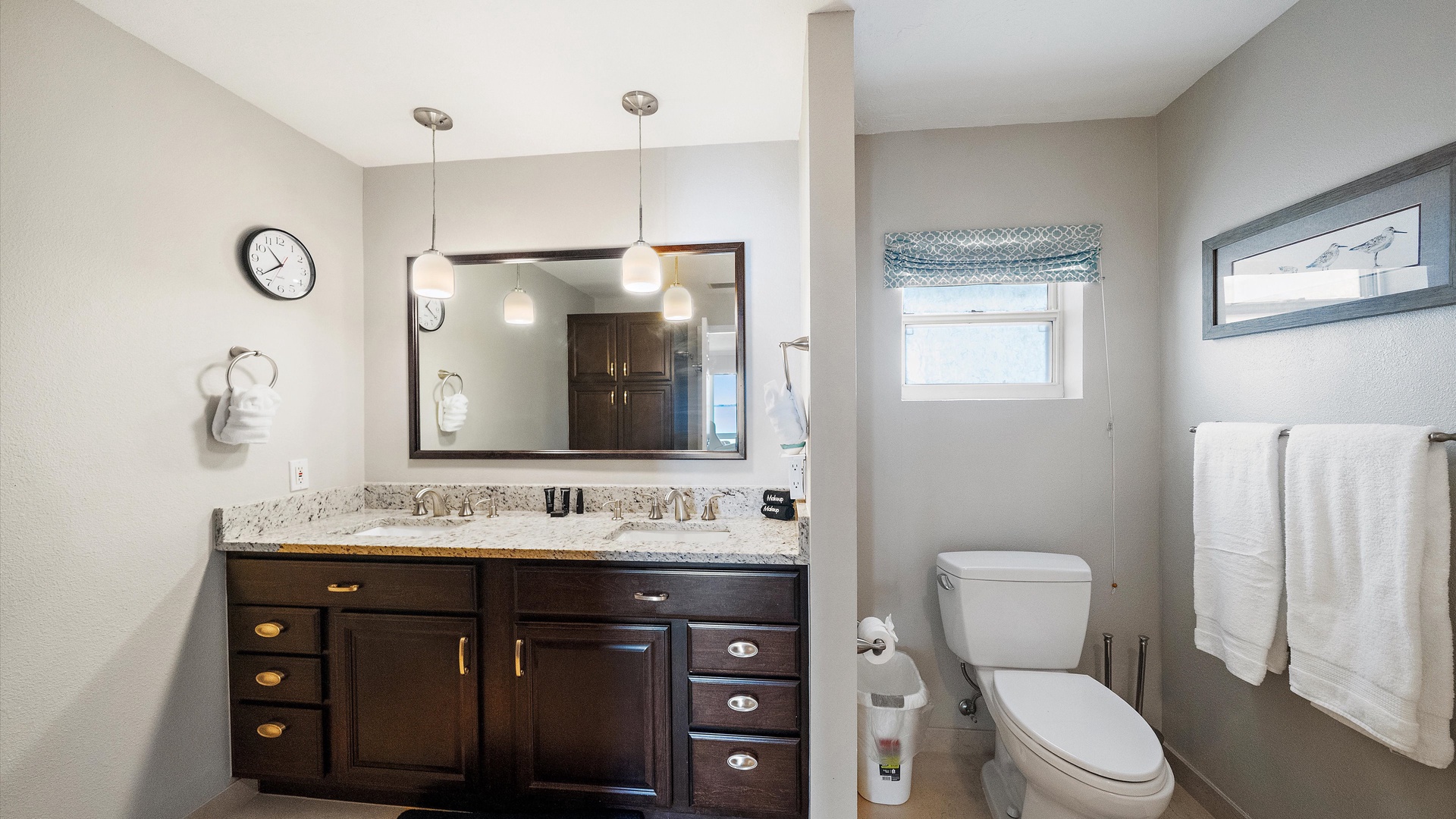 The primary bathroom features a generous double vanity, granite countertop, and warm wood cabinetry. Two sinks and ample storage add comfort to the private suite.