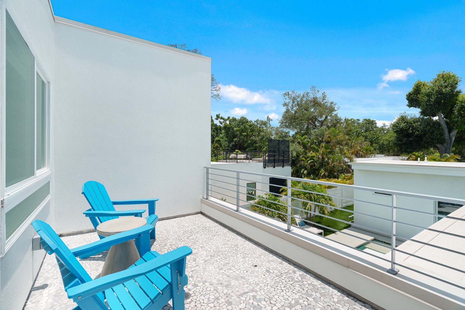 Unwind in bright blue Adirondack chairs on your private balcony, where sunny skies and lush greenery create the perfect backdrop for your morning coffee or evening relaxation.