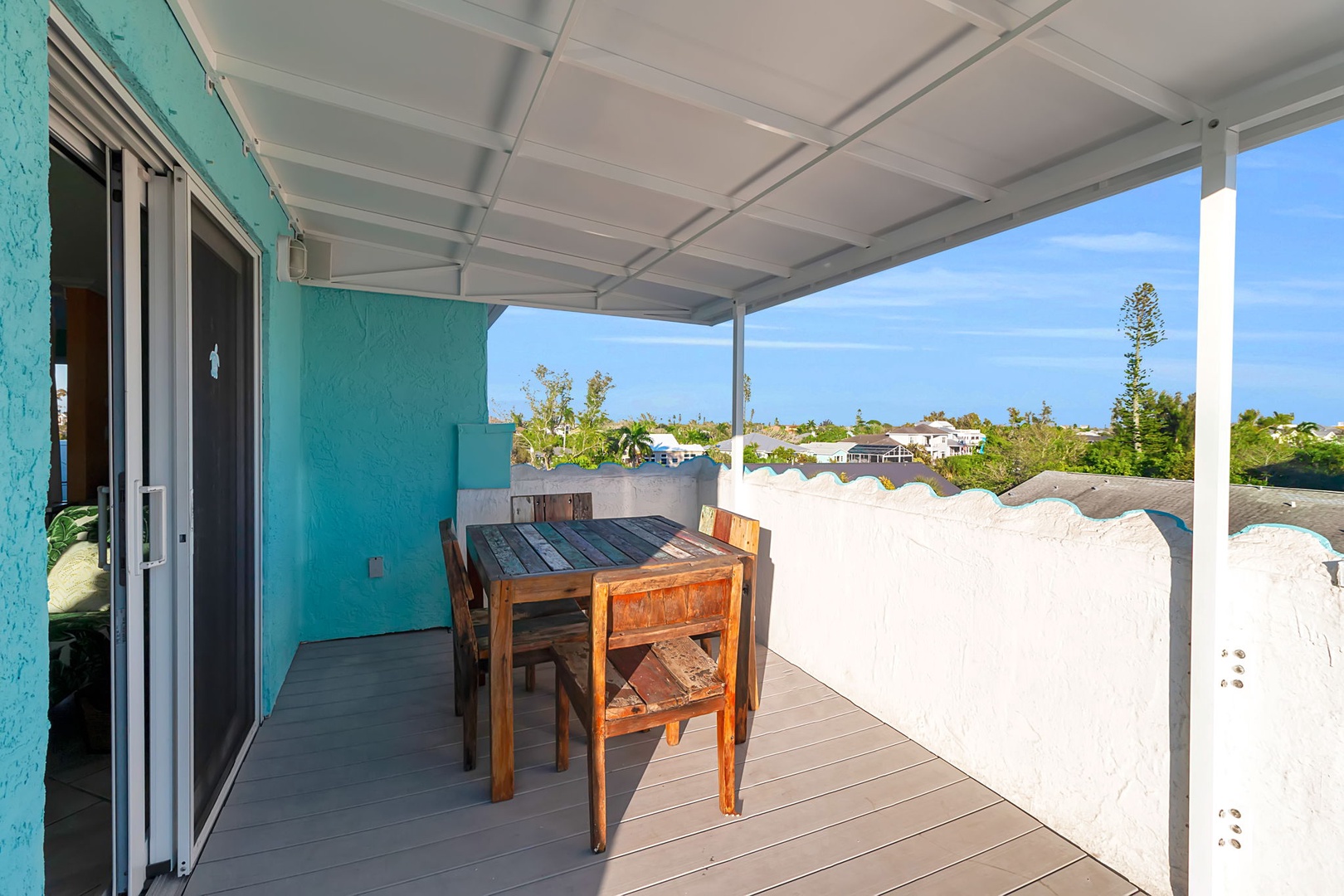 Step out onto your private terrace and settle into a relaxing meal beneath the cool shade, where vibrant turquoise walls and a decorative parapet frame views of the sunny neighborhood.