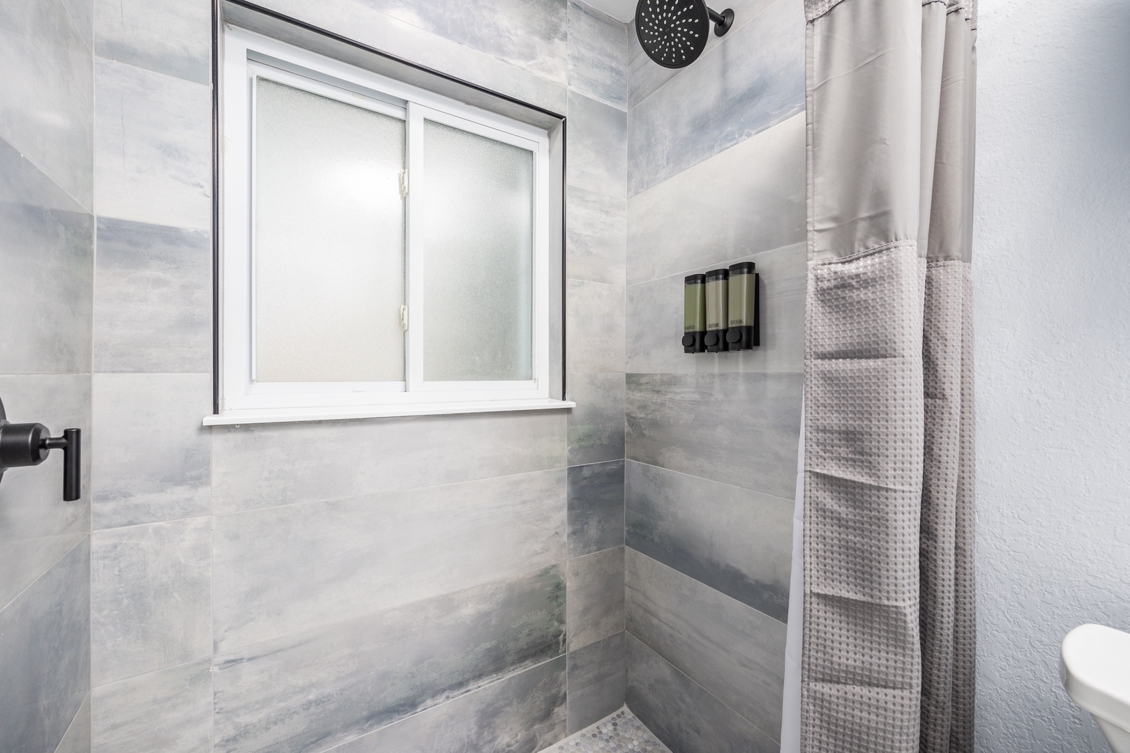 Step into your private spa-like shower with elegant marble walls, rainfall showerhead, and plush towels awaiting your arrival.
