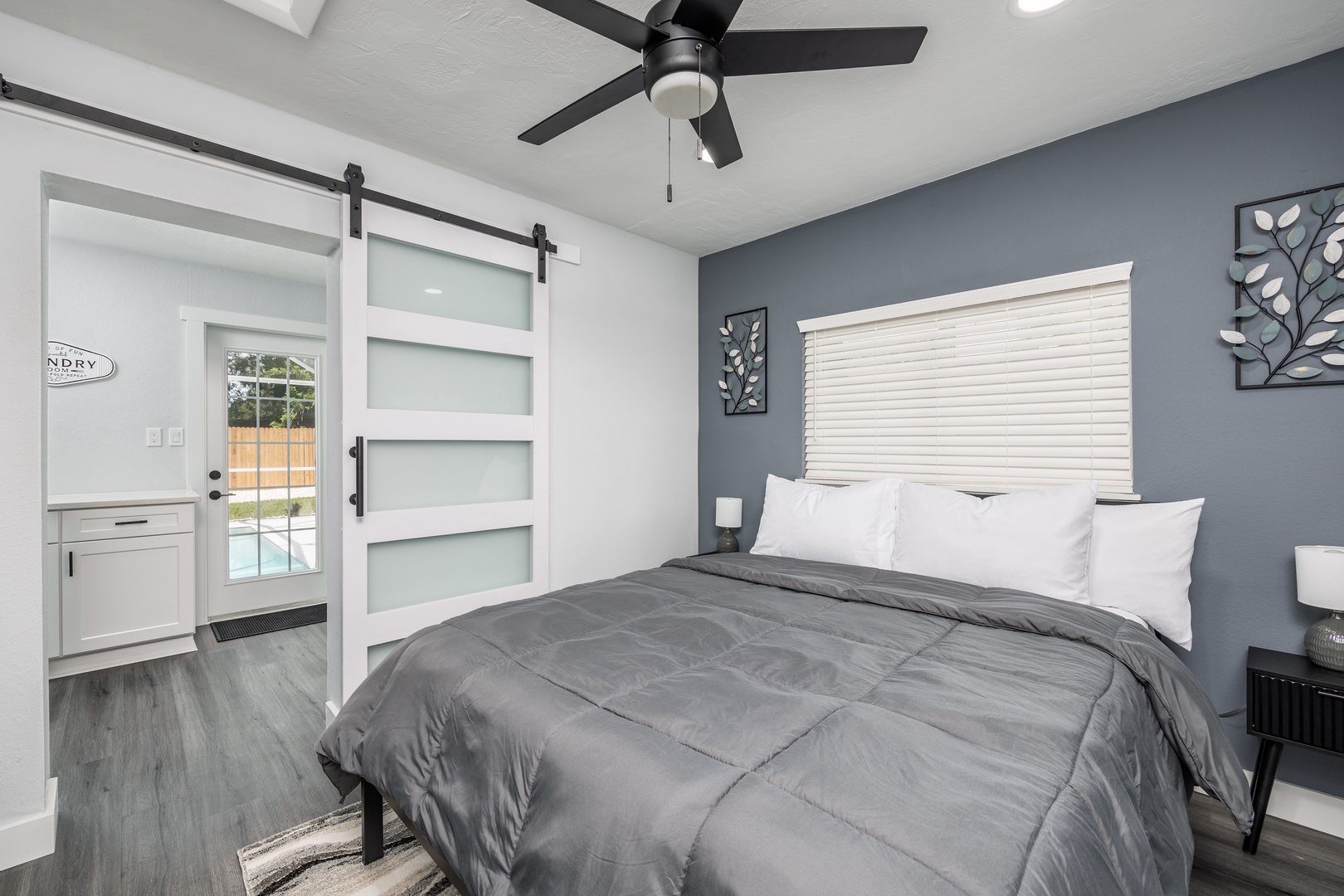 Sink into crisp white linens and let the ceiling fan create your perfect breeze in this modern bedroom sanctuary.