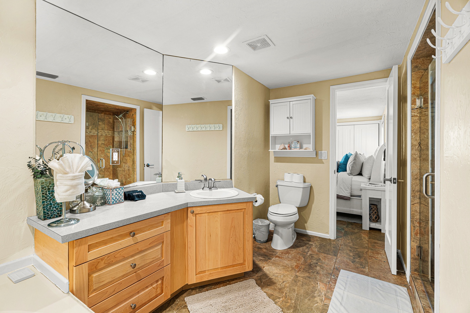Step into your spacious ensuite bathroom featuring warm wood cabinetry, gleaming countertops, and a walk-in shower with elegant tiling—ready for your morning routine or unwinding after a day of adventure.