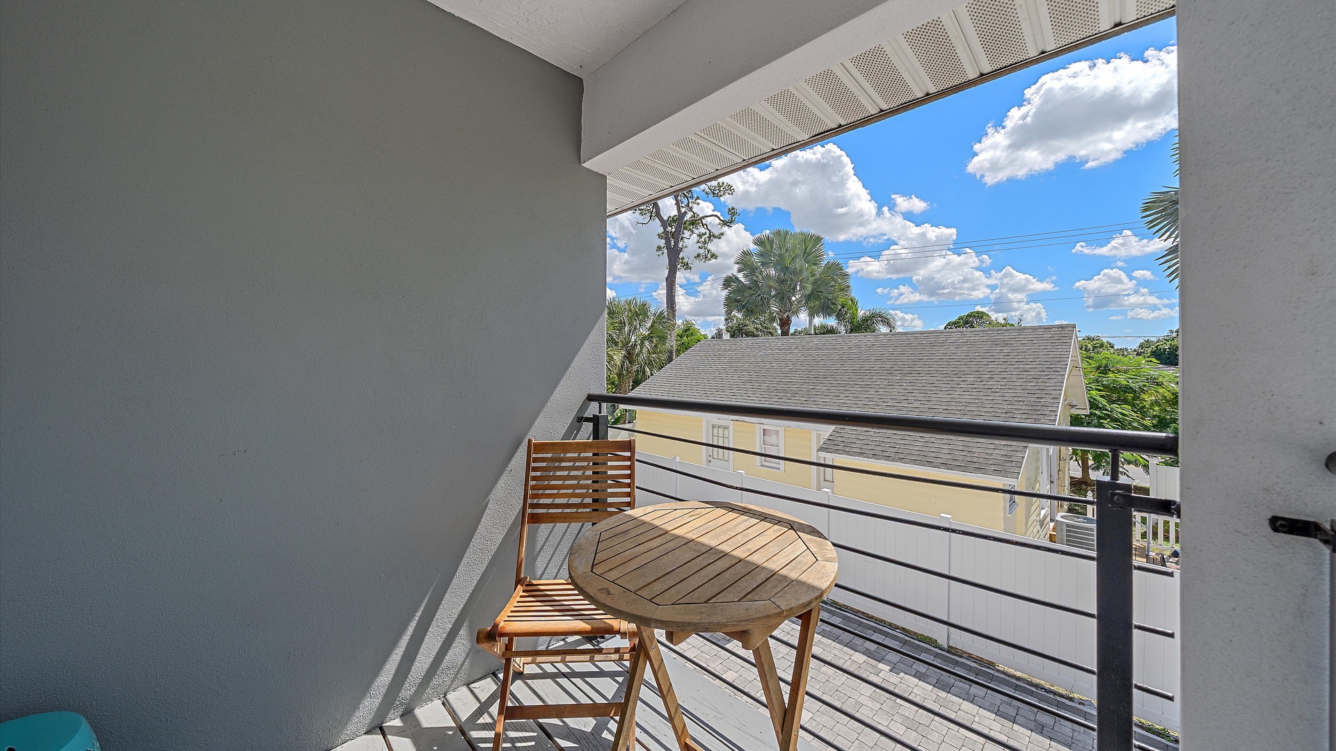 Step onto your private balcony with folding café seating, where palm trees sway under sunny skies and peaceful neighborhood views create the perfect backdrop for morning coffee or evening relaxation.