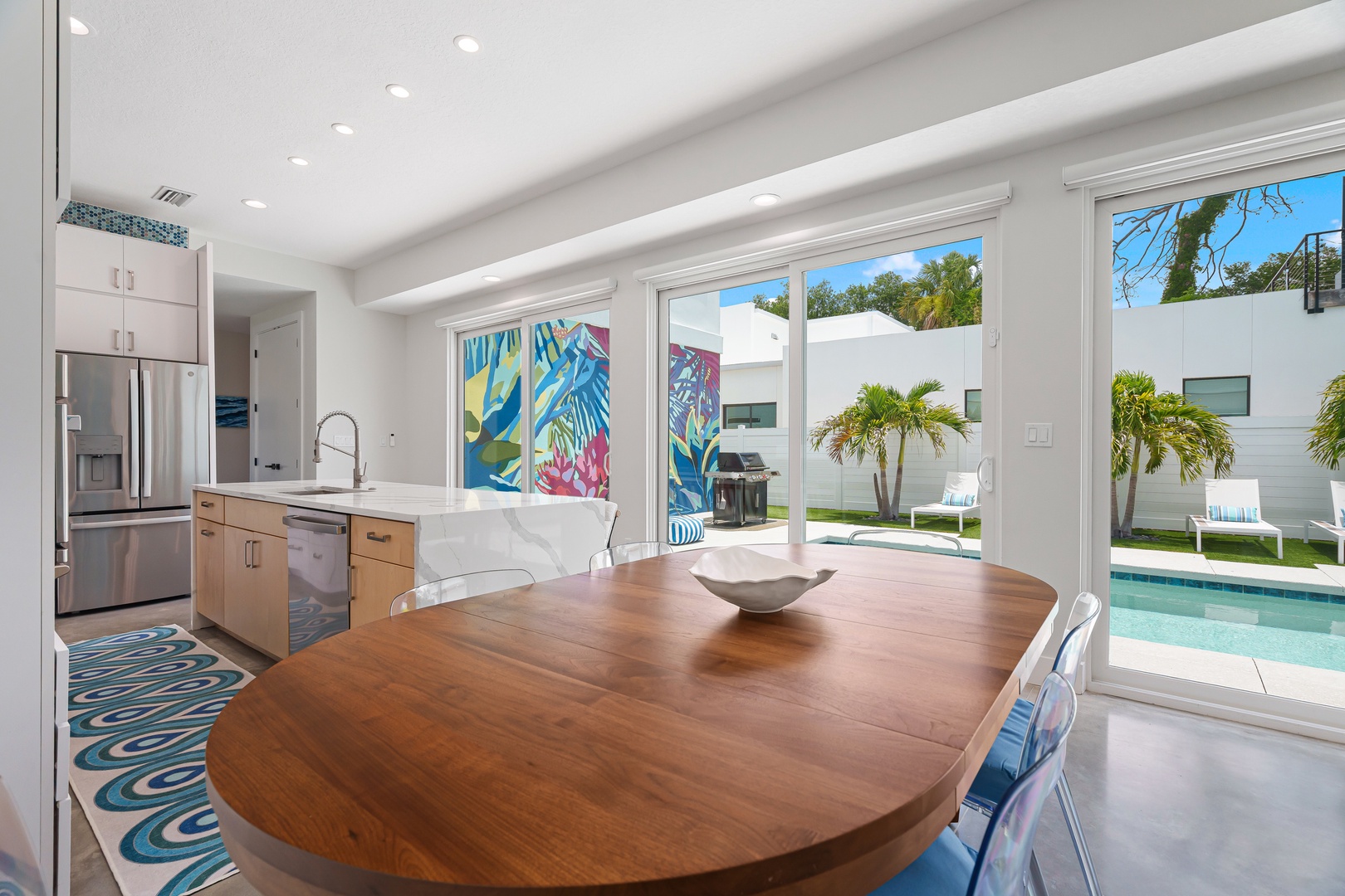 Picture yourself enjoying morning coffee at this handcrafted wooden table, framed by tropical palms and sparkling pool views just beyond the glass doors—your private retreat awaits.
