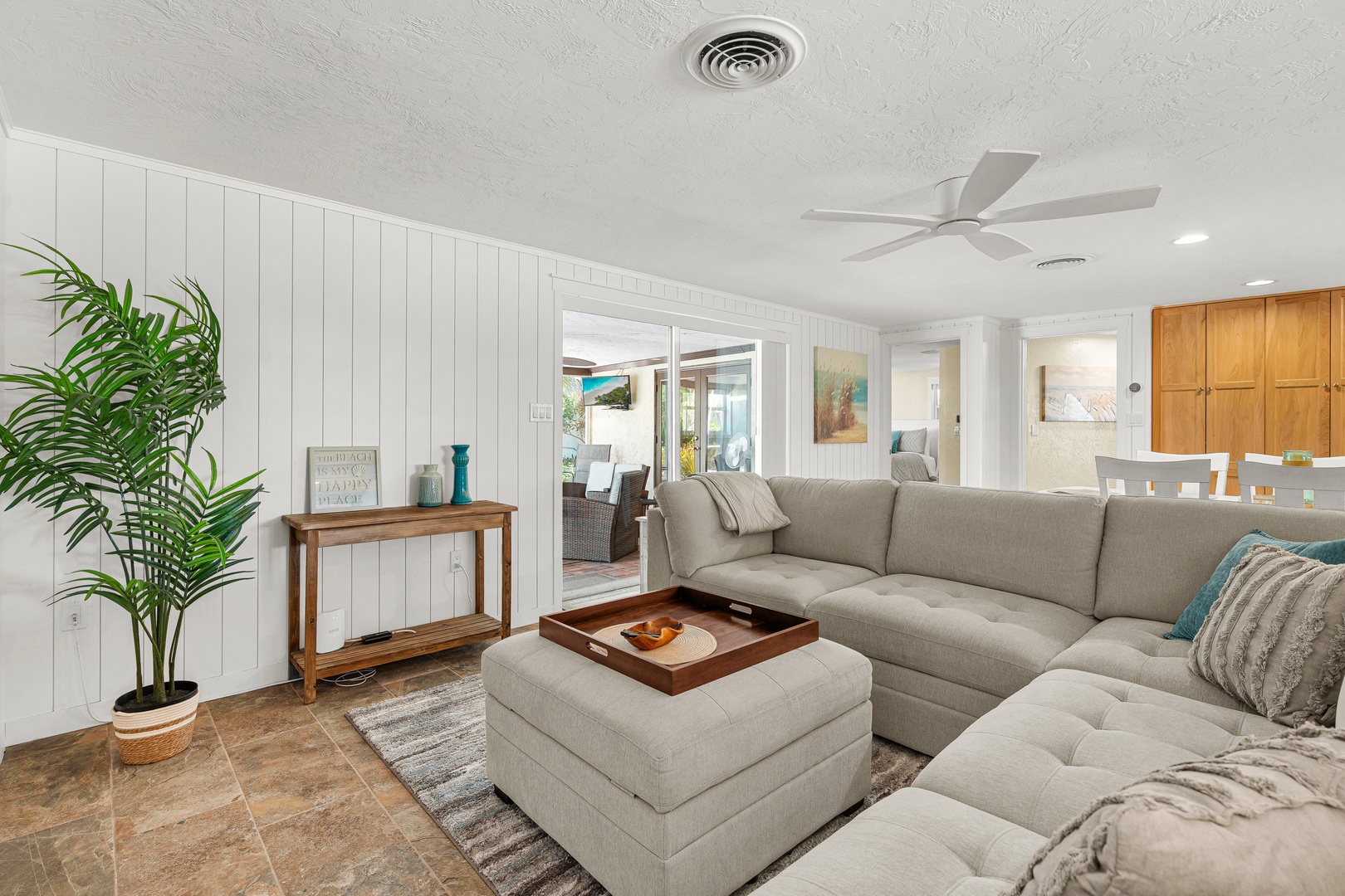 Sink into the plush sectional and unwind in your bright, coastal-inspired living space. Fresh white shiplap and breezy ceiling fans set the scene for lazy afternoons and relaxed evenings together.