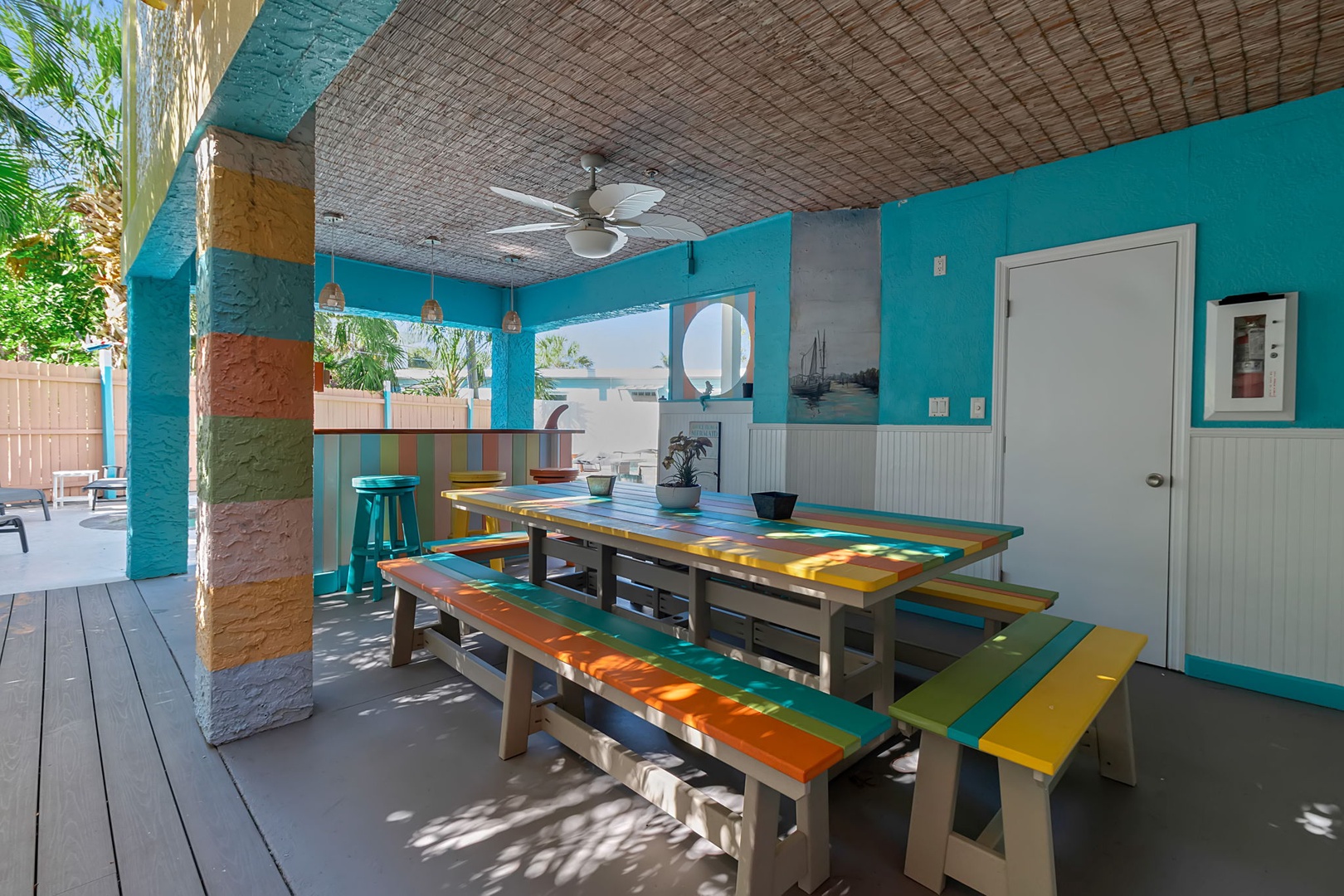 Step into your own tropical oasis with a vibrant outdoor dining area, where colorful picnic tables and artistic touches create the perfect spot for morning coffee or sunset gatherings.