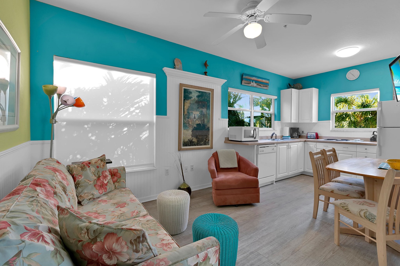 Step into your bright and welcoming living space, where cheerful turquoise walls and cozy furnishings invite you to unwind. Palms sway just outside your windows, creating a peaceful tropical retreat.