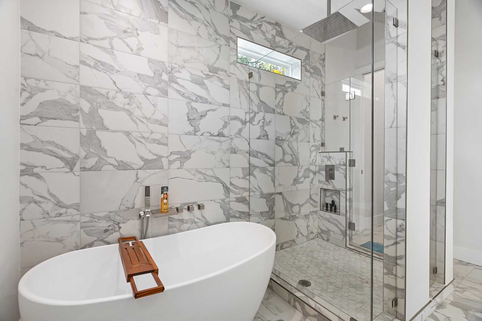 Relax in your private spa-like sanctuary featuring a luxurious soaking tub and spacious walk-in shower with elegant marble finishes throughout.