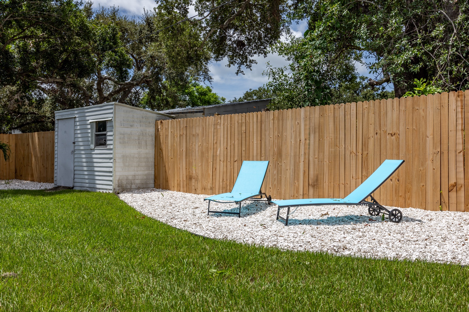 Stretch out on your private sunbeds in this peaceful backyard retreat, surrounded by lush greenery and privacy fencing for ultimate relaxation.